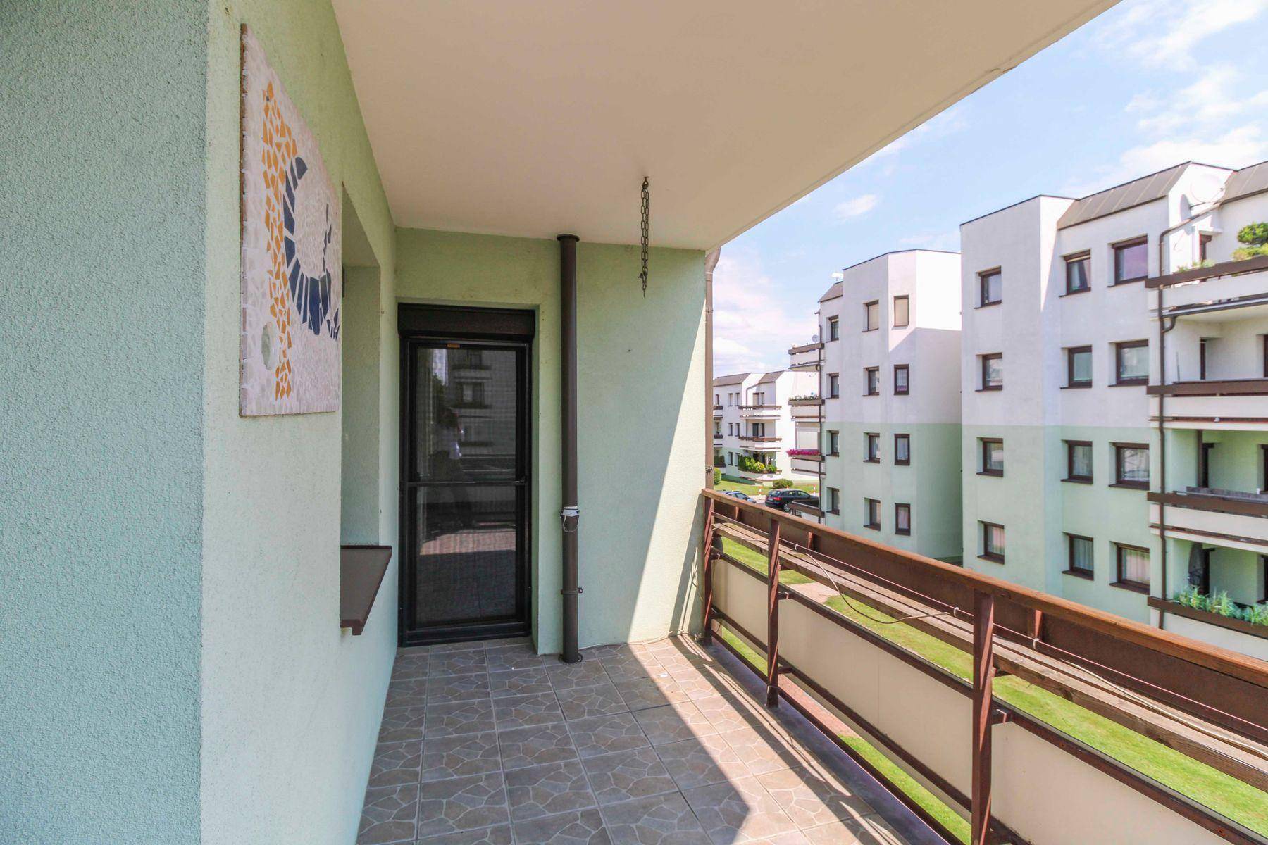 Heller Balkon mit Zugang zum Innenbereich und Blick auf die Wohnanlage.