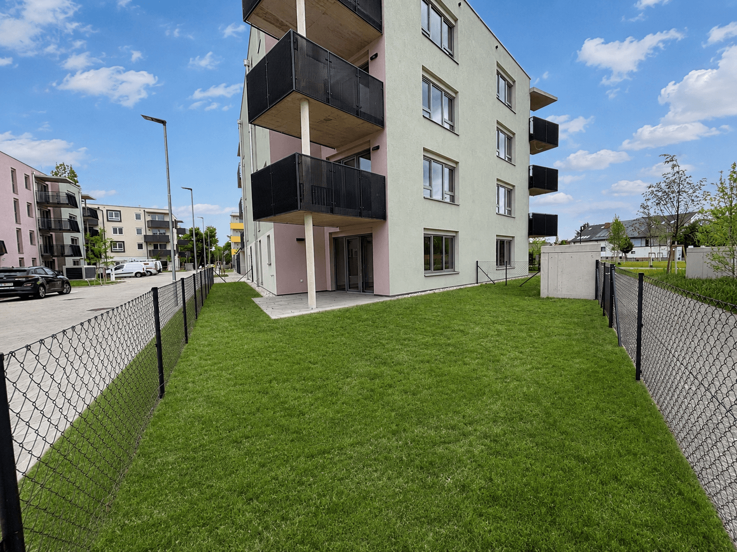 Gepflegte Rasenfläche vor einem modernen Mehrfamilienhaus mit Balkonen.