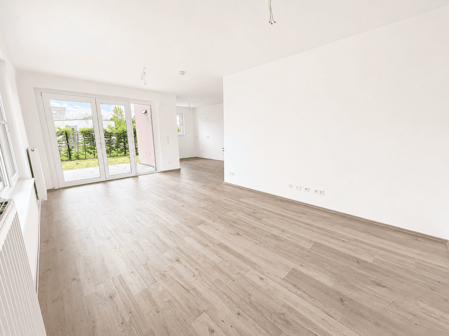 Offener Wohnbereich mit Laminatboden, viel Tageslicht und Zugang zur Terrasse und zum Garten.