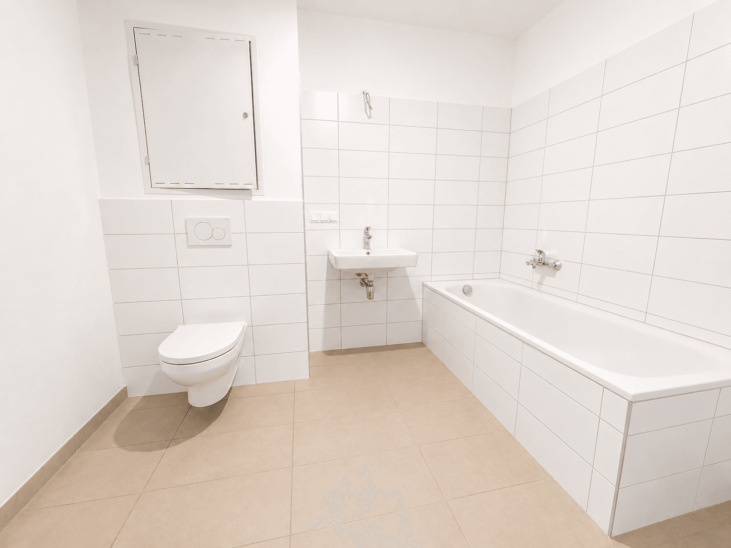 Modernes Badezimmer mit weißen Fliesen, Badewanne, Toilette und Waschbecken.