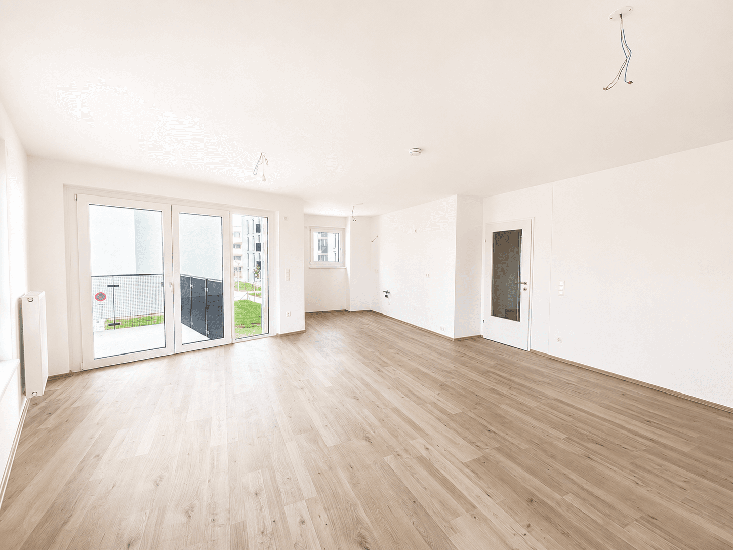 Geräumiges, helles Wohnzimmer mit Laminatboden und direktem Zugang zum Garten.
