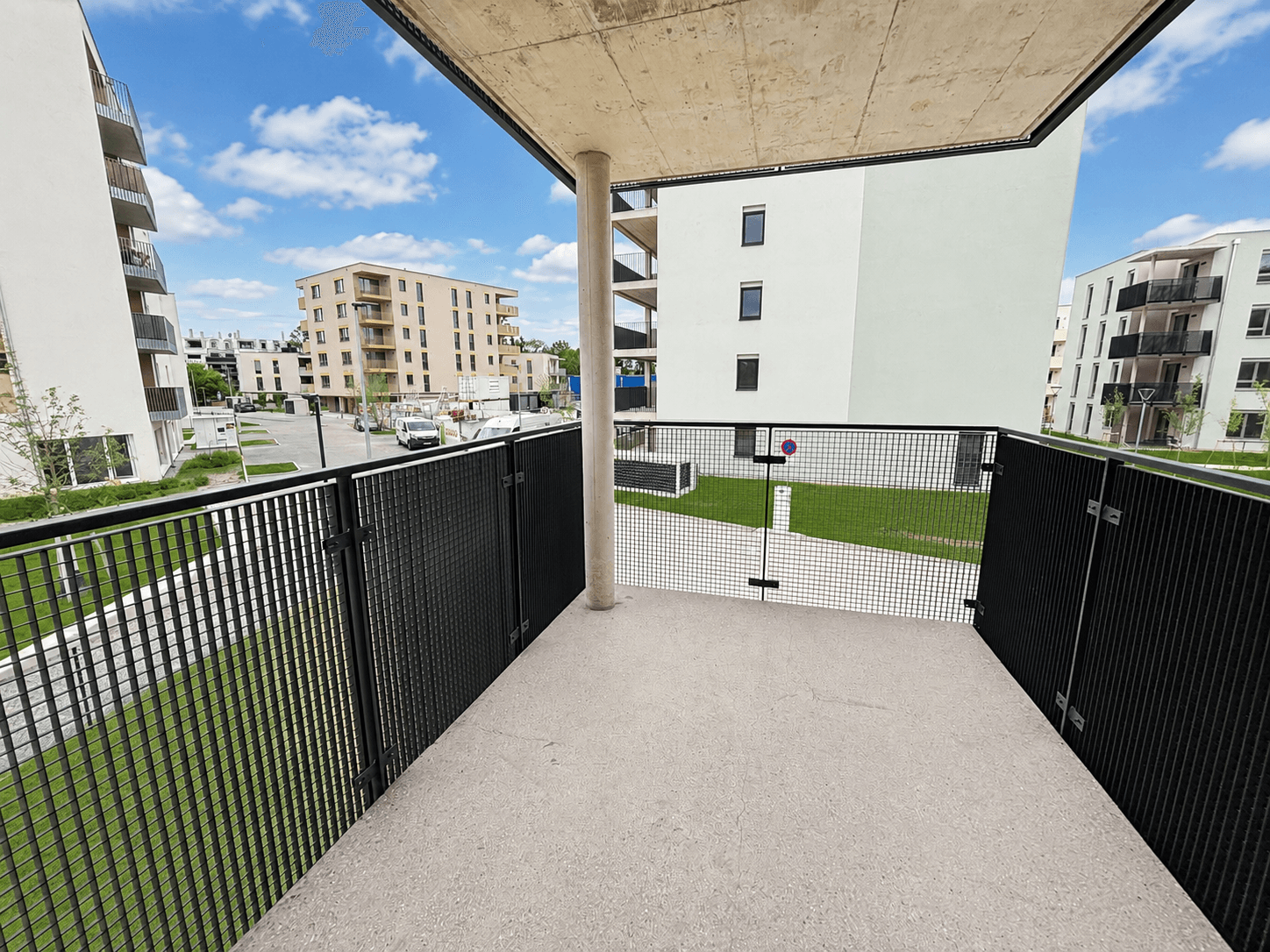 Moderner Balkon mit Metallgeländer und Blick auf die umliegenden Neubauten.