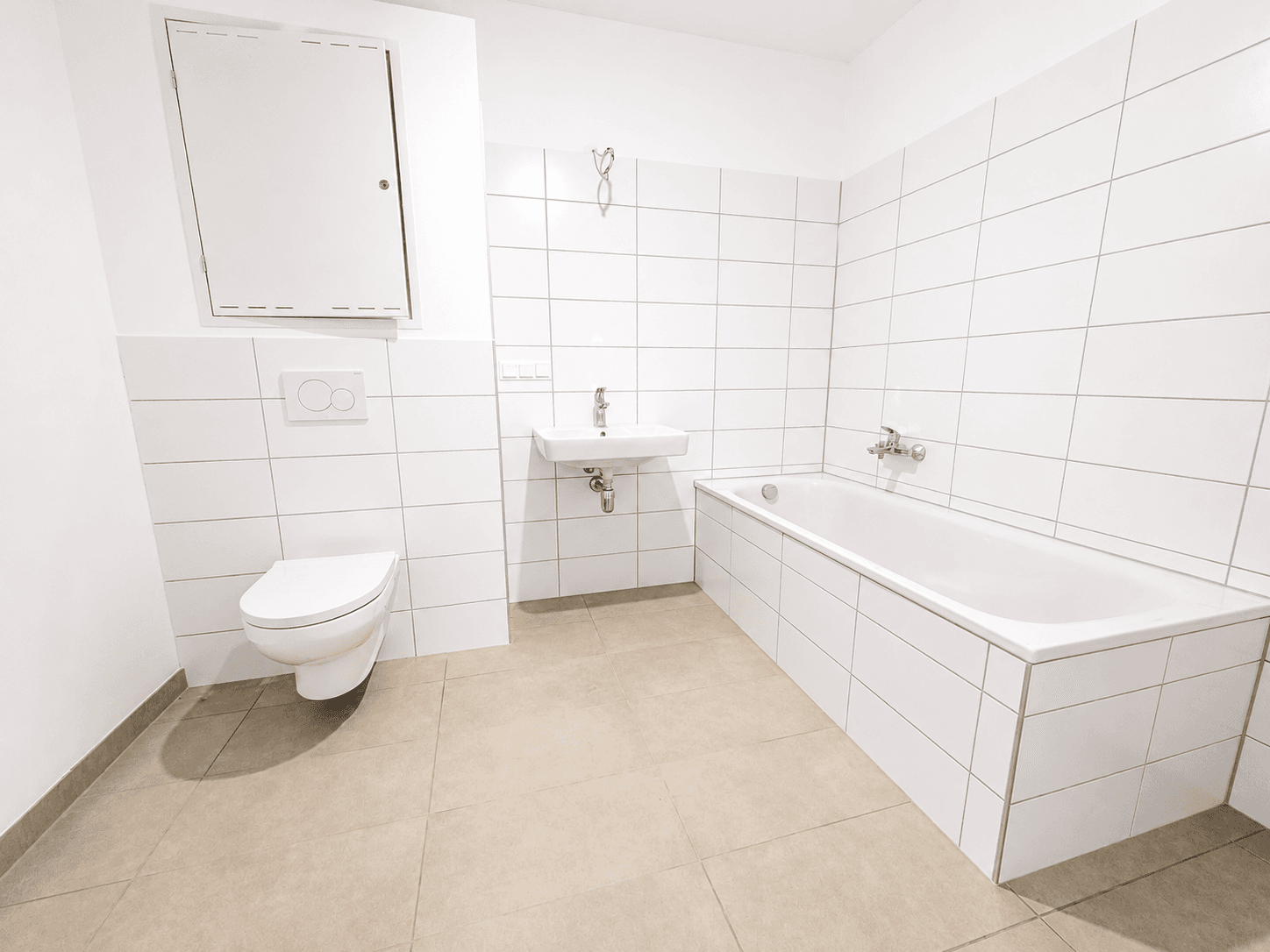 Modernes Badezimmer mit weißen Fliesen, Badewanne, WC und Waschbecken.