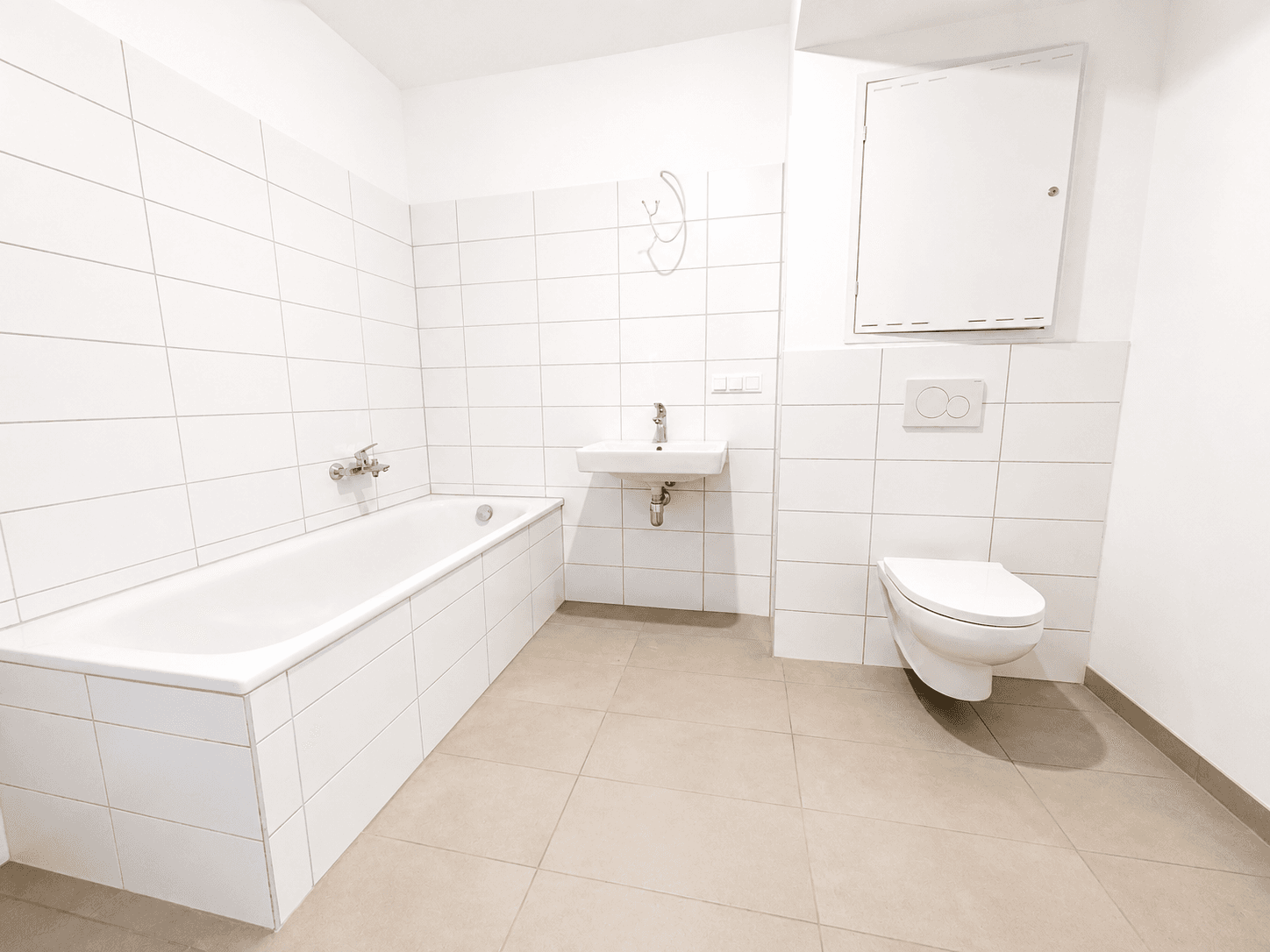 Modernes Badezimmer mit Badewanne, Wand-WC und hellen Fliesen.