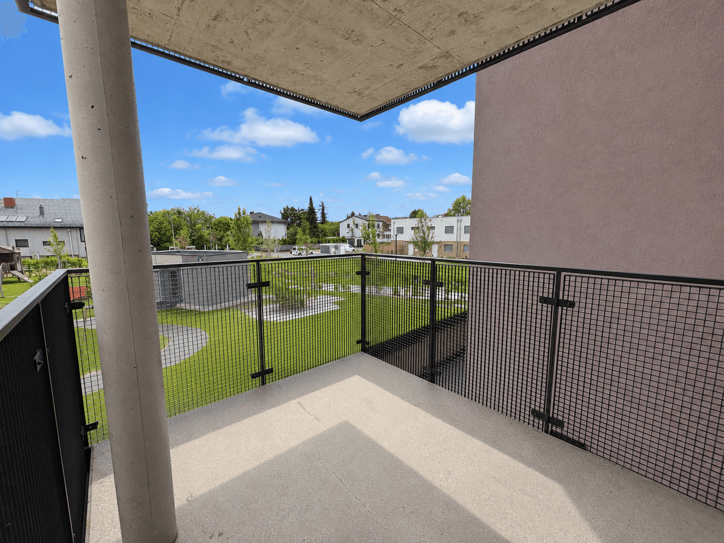 Moderner Balkon mit Metallgeländer und Blick auf die grüne Umgebung.