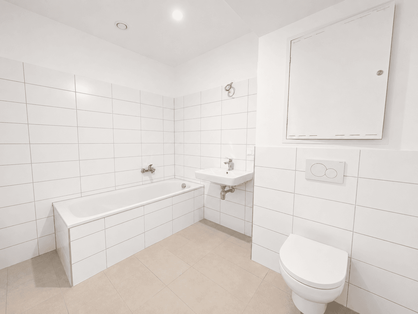 Modernes Badezimmer mit weißen Fliesen, Badewanne, wandhängendem WC und einem einzelnen Waschbecken.