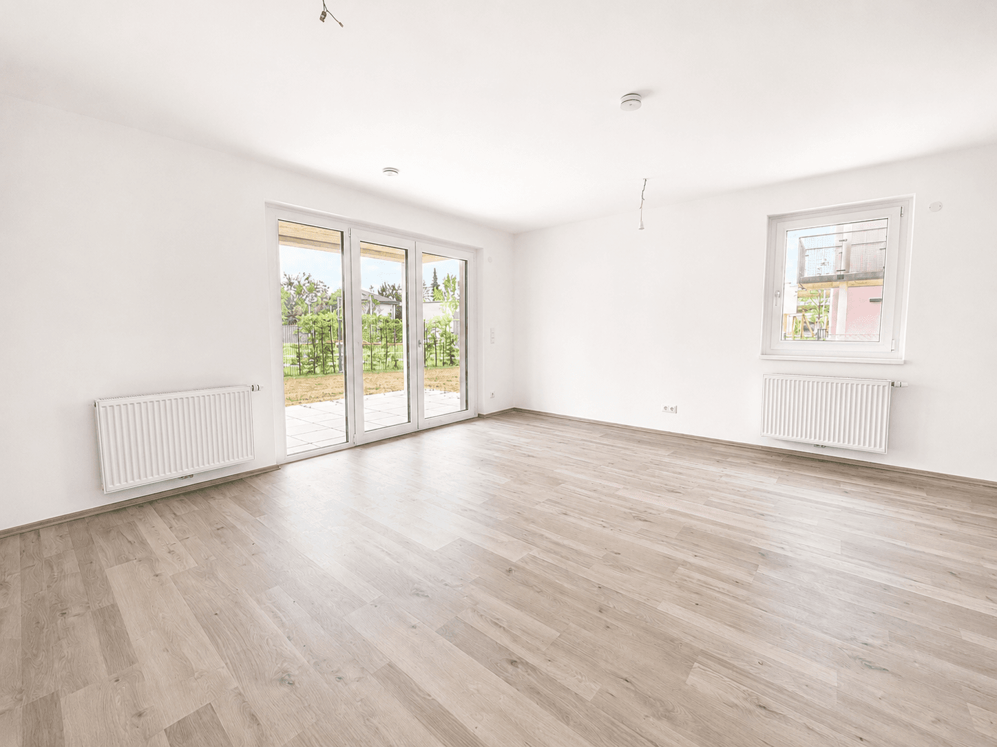 Heller Wohnbereich mit großen Schiebetüren zum Garten und einem zusätzlichen Fenster.