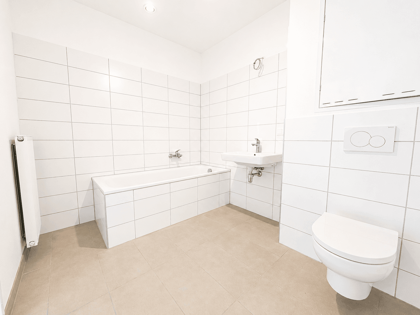 Modernes Badezimmer mit weißen Fliesen, Badewanne, Waschbecken und wandhängendem WC.