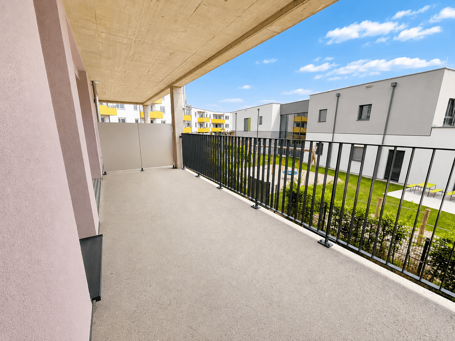 Geräumiger Balkon mit Blick auf den begrünten Innenhof und moderne Wohngebäude.