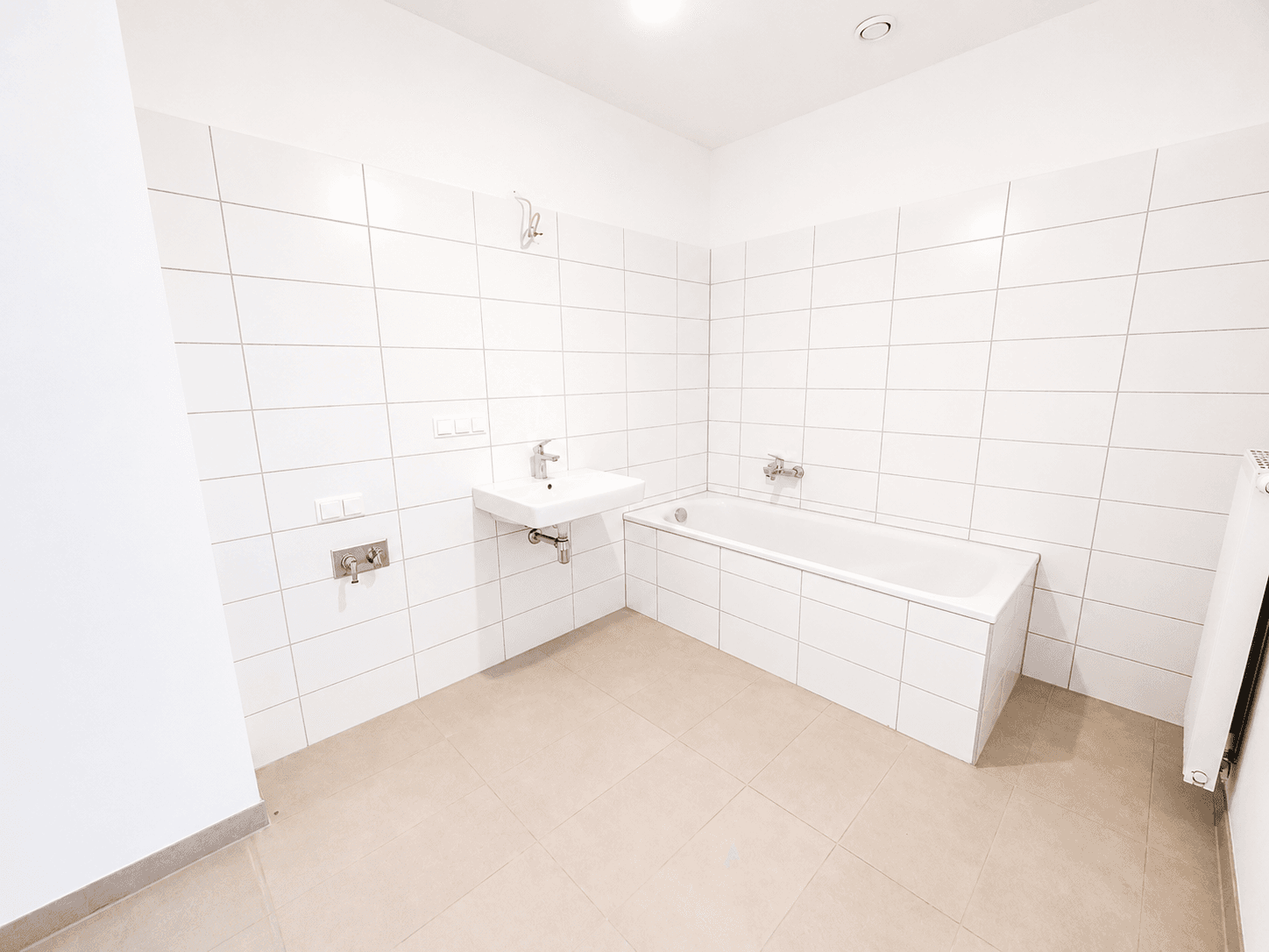 Modernes Badezimmer mit weißen Fliesen, Badewanne und Waschbecken.