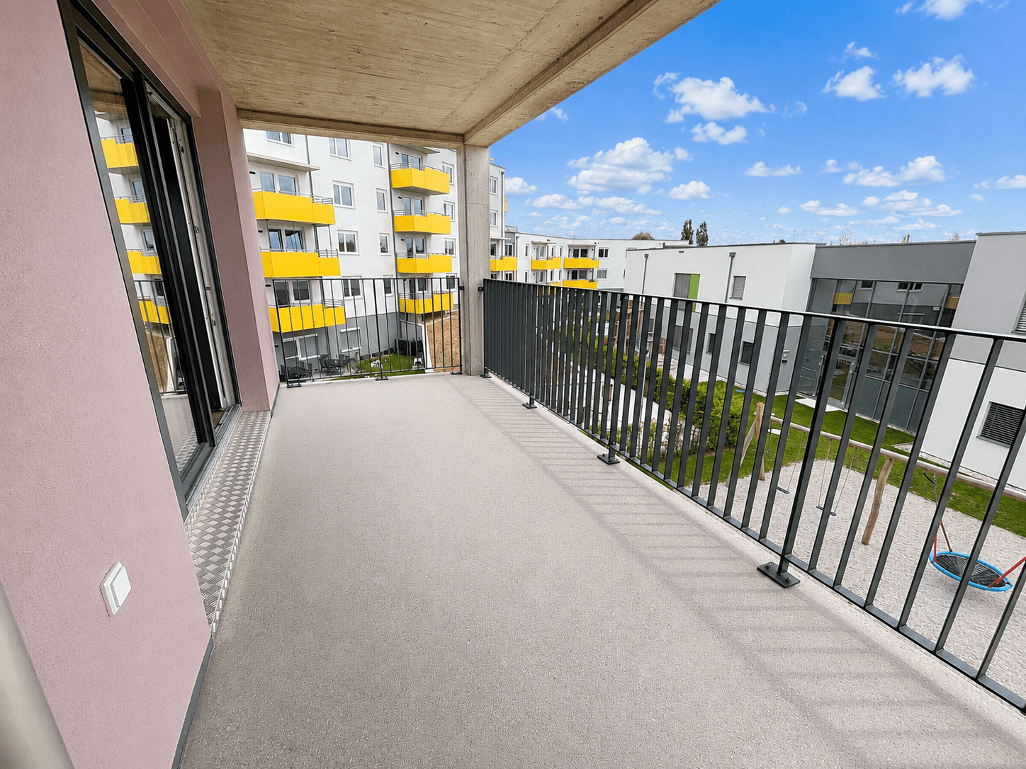 Geräumiger Balkon mit Blick auf den Innenhof und den Spielplatz, ideal für entspannte Stunden im Freien.