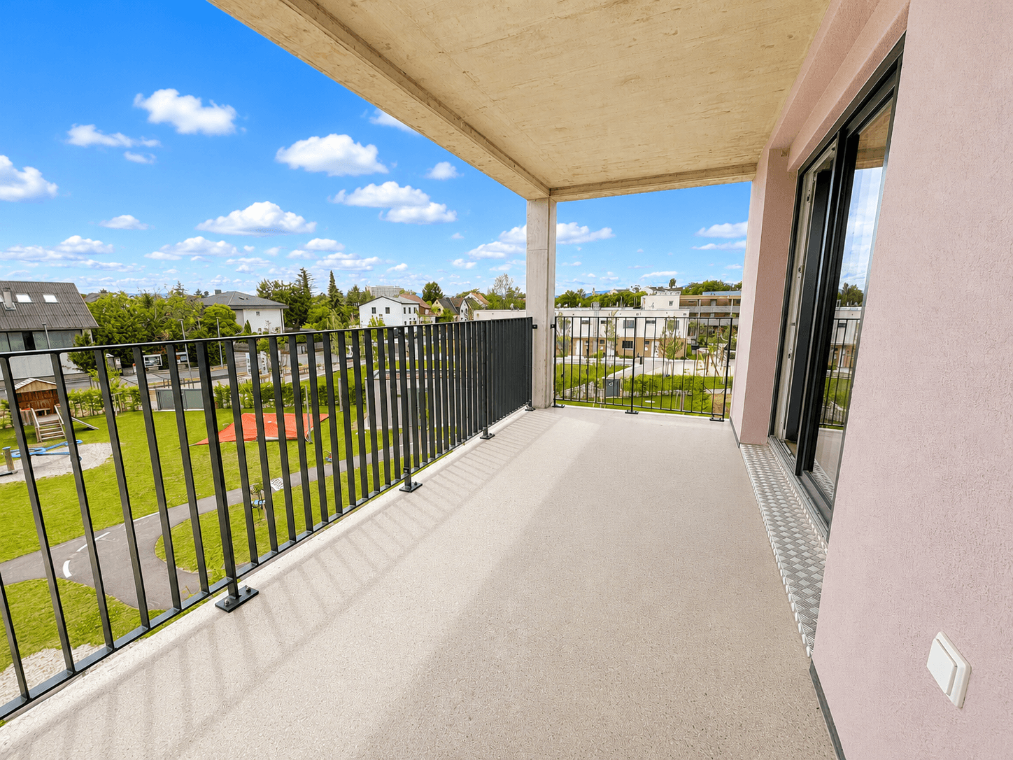 Geräumiger Balkon mit Blick auf die grüne Umgebung und einen Spielplatz.