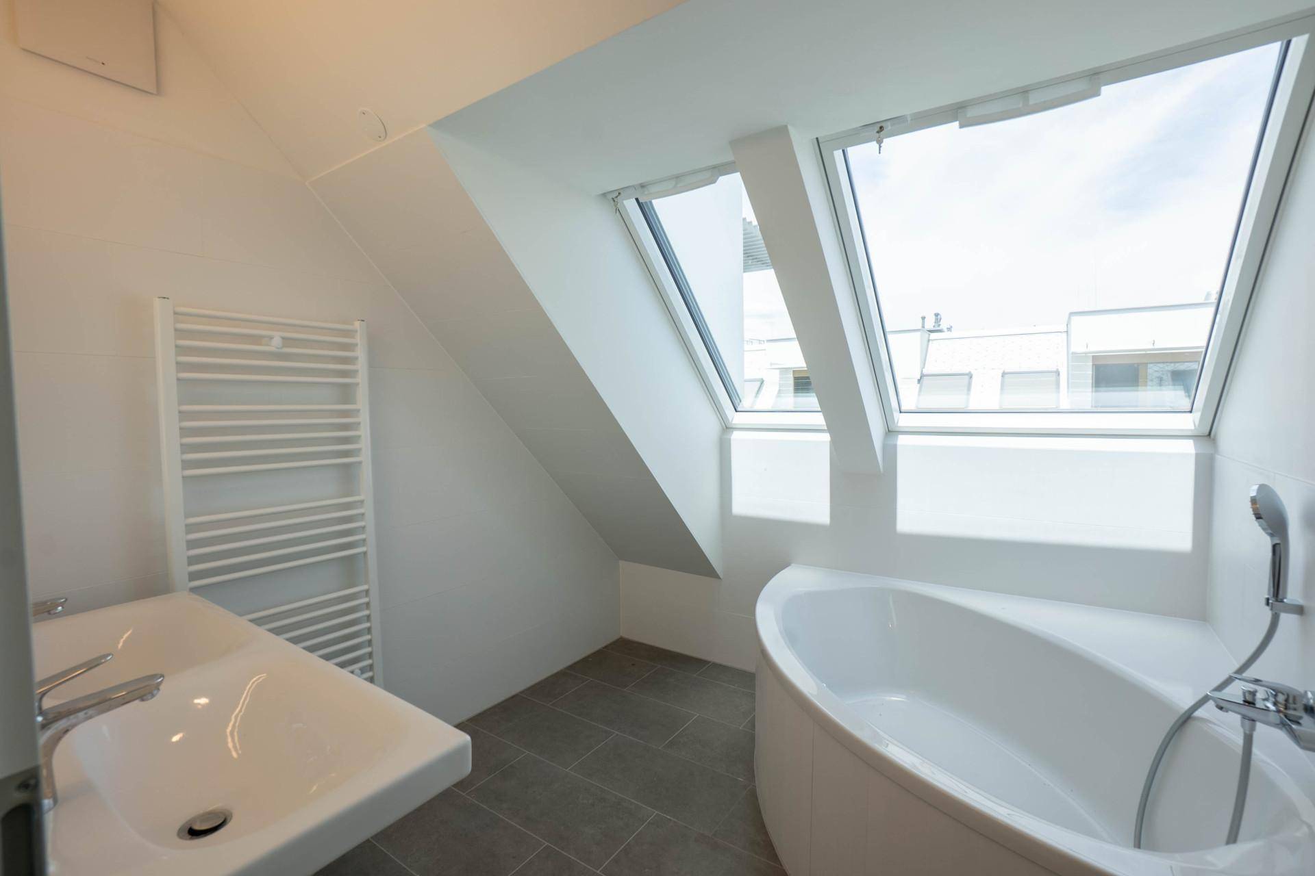 Modernes Badezimmer mit Eckbadewanne, großem Dachfenster und beheiztem Handtuchhalter.