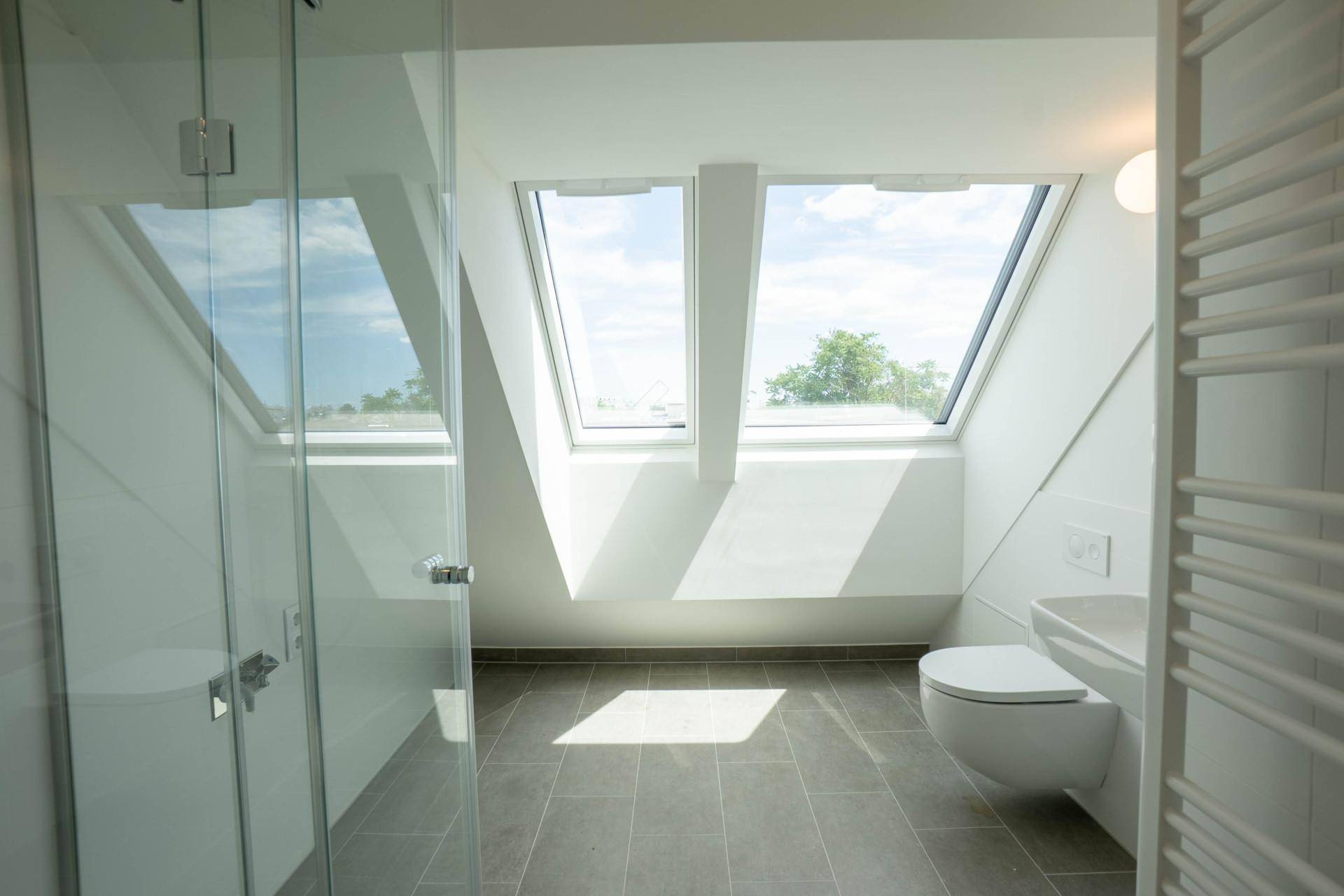 Modernes Badezimmer im Dachgeschoss mit großen Dachfenstern, Dusche und Wand-WC.