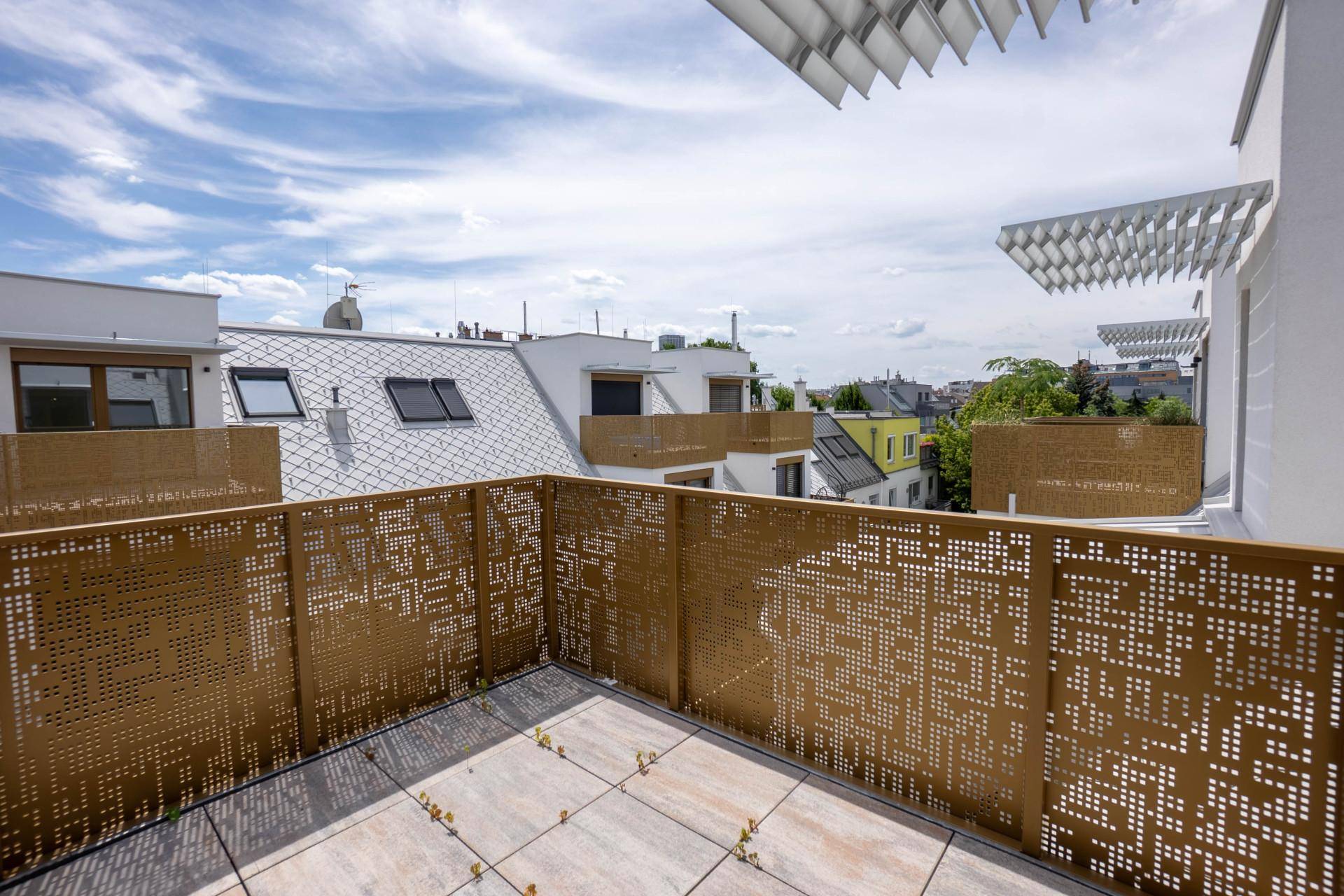 Geräumiger Balkon mit dekorativem Metallgeländer und Fliesenboden, bietet Blick über die Dächer.
