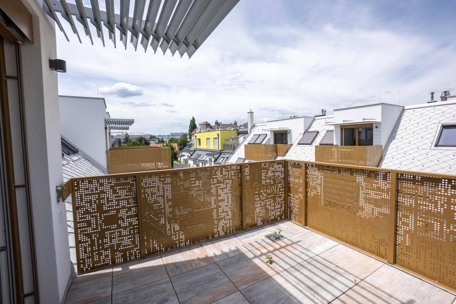Außenbereich mit modernem Balkon, perforiertem Geländer und Blick auf die Umgebung.