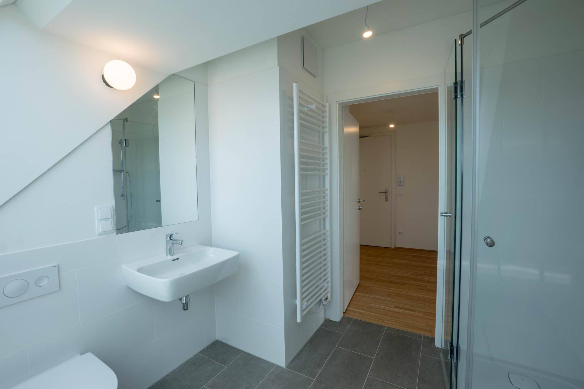 Funktionales Badezimmer mit Waschbecken, großem Spiegel und beheiztem Handtuchhalter.