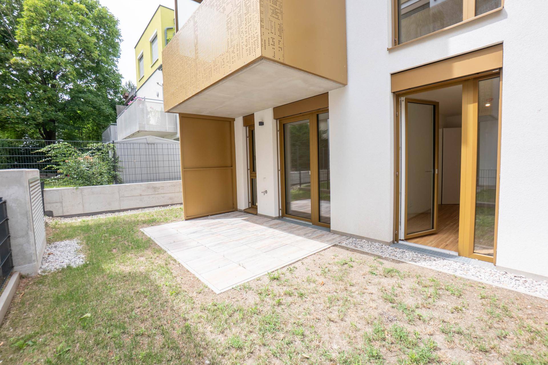 Kleine Terrasse mit Steinplatten und Rasenfläche, direkt zugänglich vom Wohnbereich.