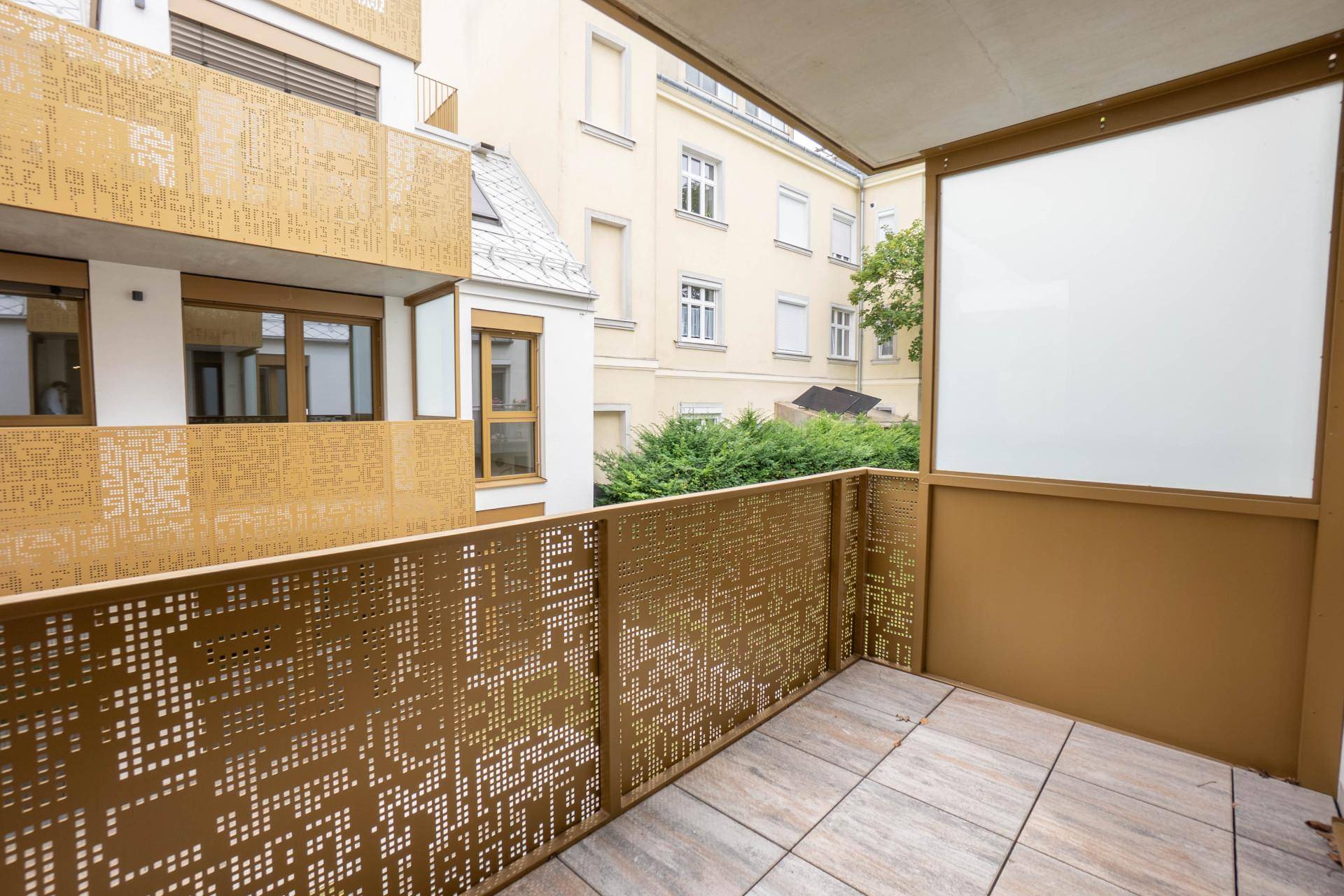 Ein Balkon mit dekorativem Metallgeländer und Blick auf den Innenhof des Gebäudes.