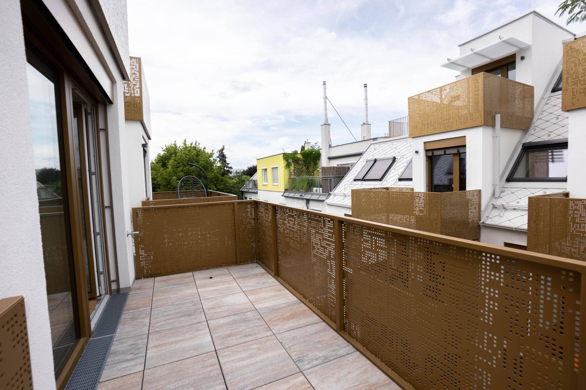 Großer Balkon mit modernen, perforierten Metallgeländern und Fliesenboden.