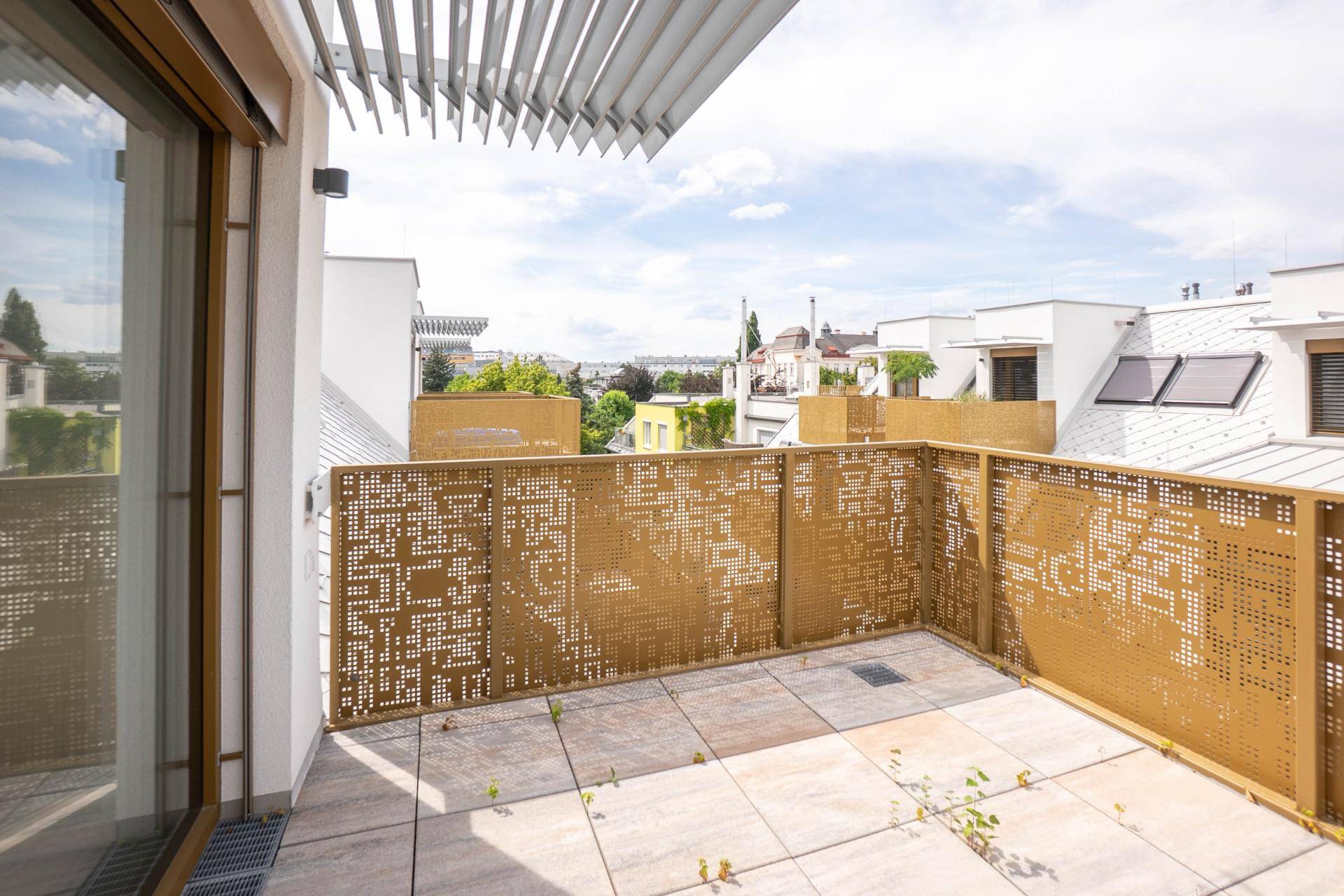 Geräumige Dachterrasse mit modernen Fliesen und dekorativem Metallgeländer, umgeben von Gebäuden.