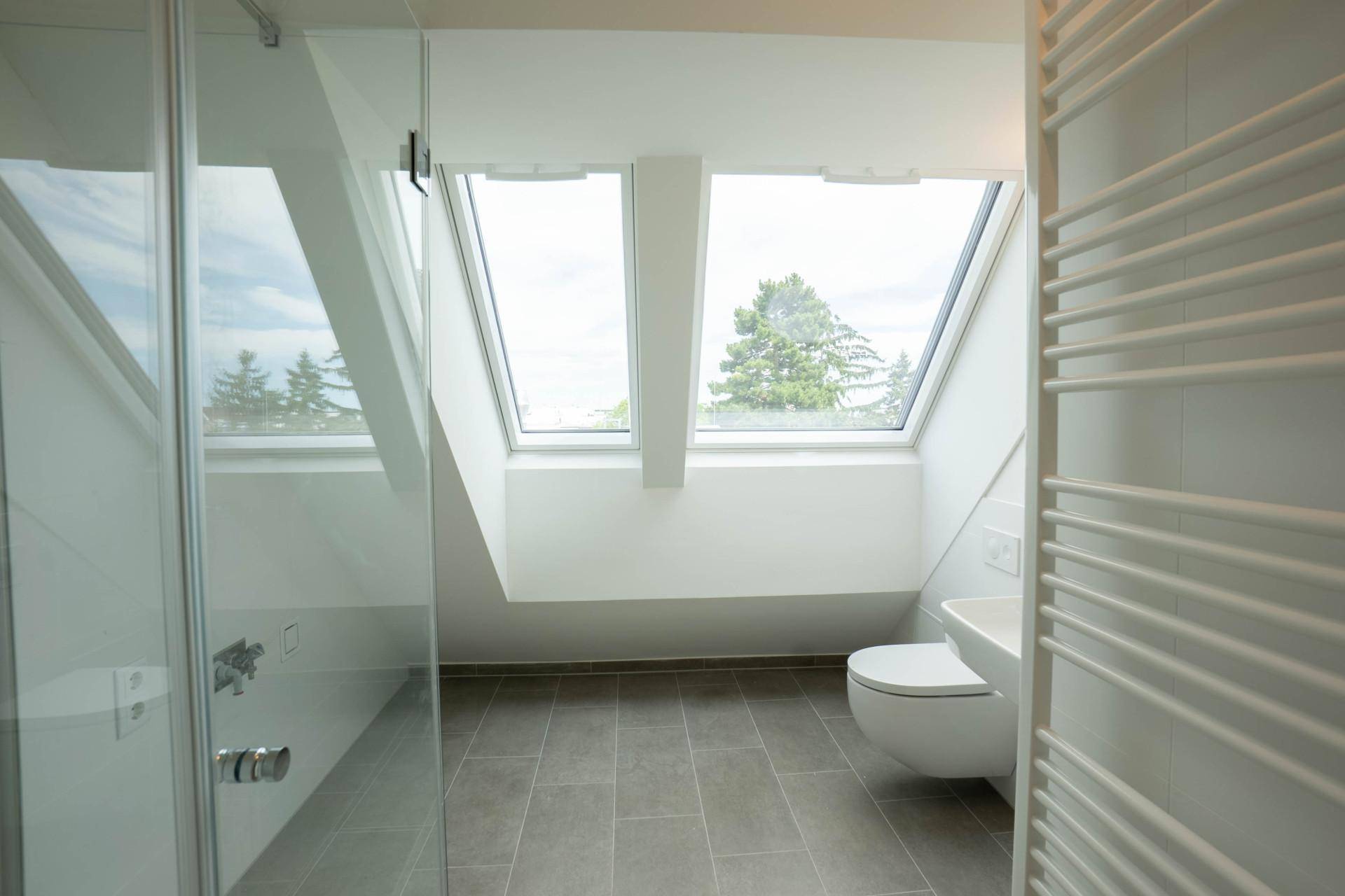 Helles modernes Badezimmer im Dachgeschoss mit Schrägdach, Dusche, Wand-WC und Dachfenstern.