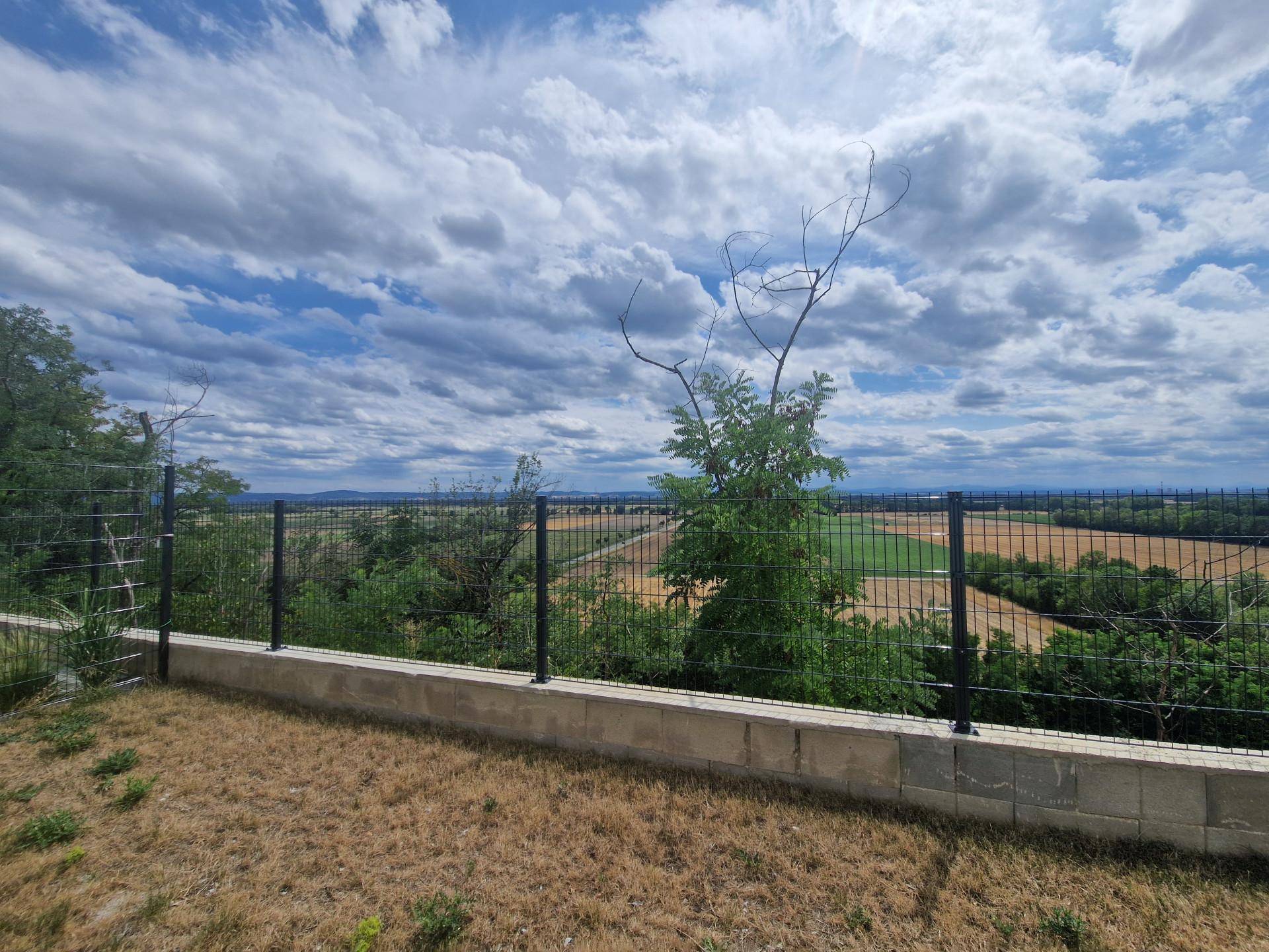 Garten mit Zaun und Panoramablick auf die weite Landschaft und Felder.