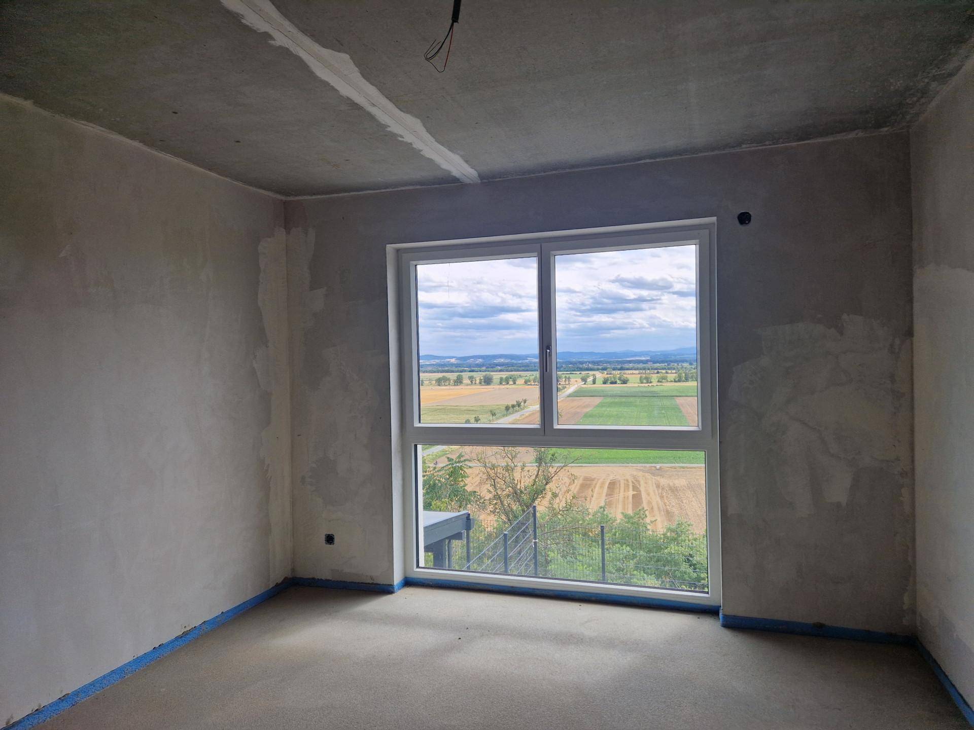 Unfertiges Zimmer mit großem Fenster, das einen weiten Blick auf die Landschaft bietet.