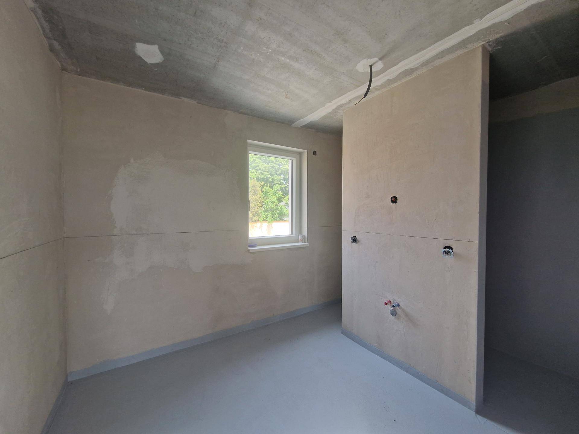 Unfertiger Raum mit Rohbauwänden und sichtbaren Installationen, bereit für den Ausbau.