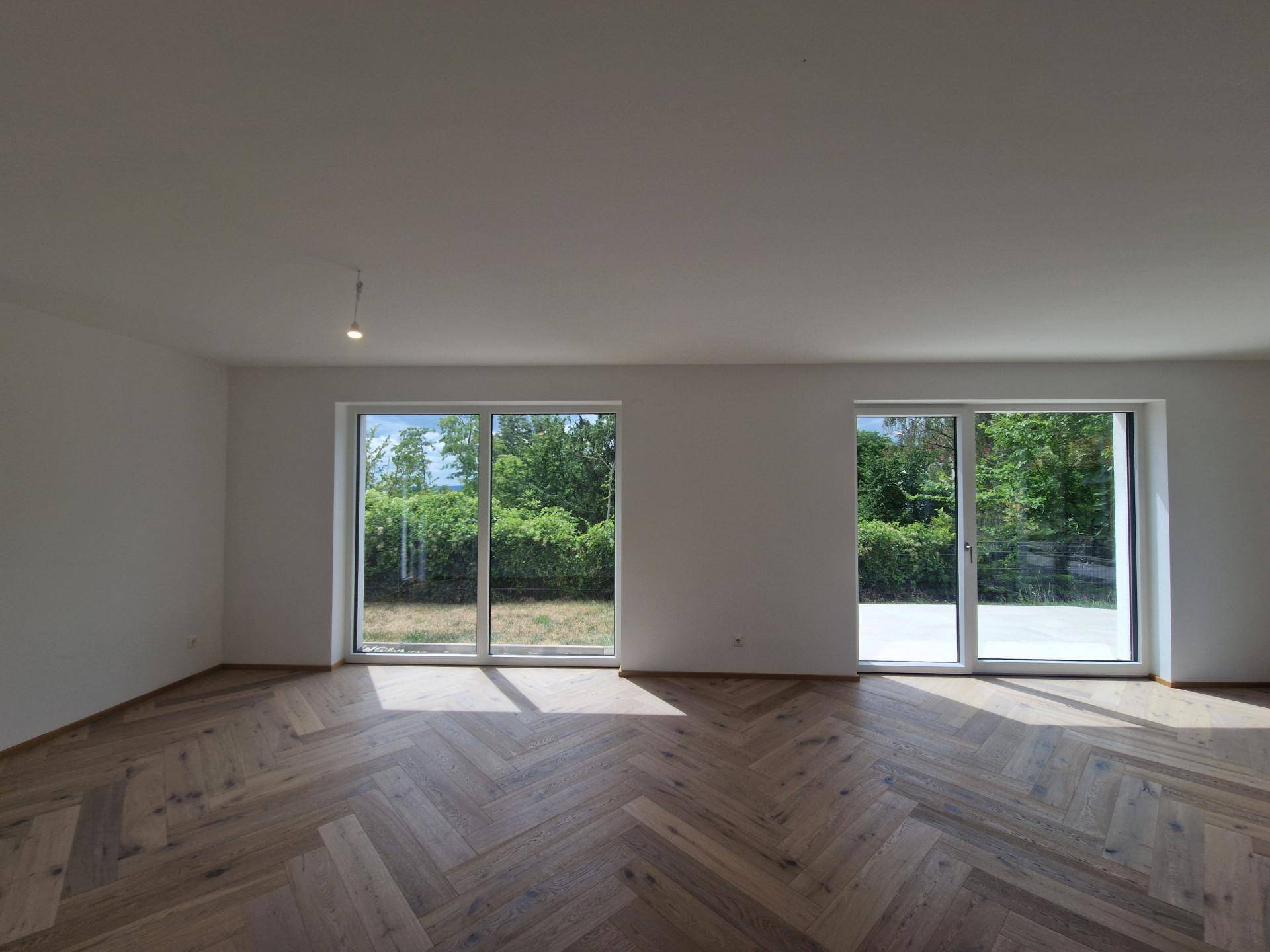 Helles Wohnzimmer mit Fischgrätparkett und großen Schiebetüren zum Garten.