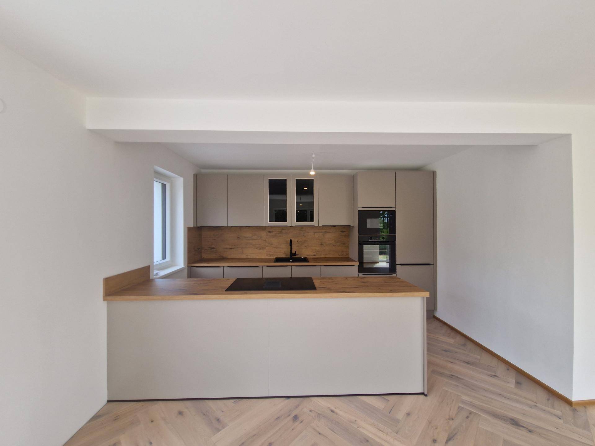 Stilvolle Küche mit Kücheninsel, hellen Schränken und Holzdetails in einem offenen Raum.