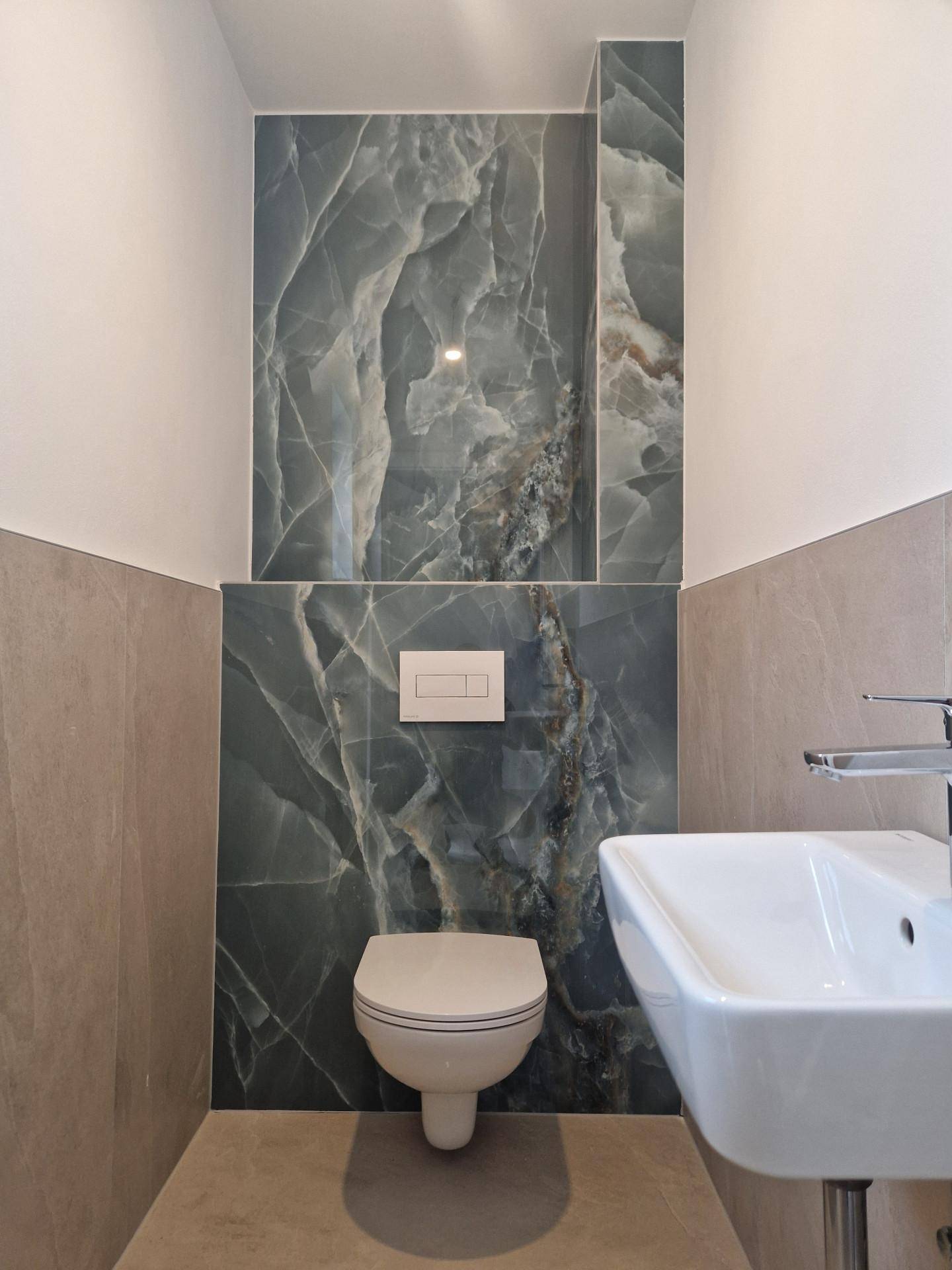 Modernes Gäste-WC mit Wand-WC, kleinem Waschbecken und auffälligen Marmorfliesen.