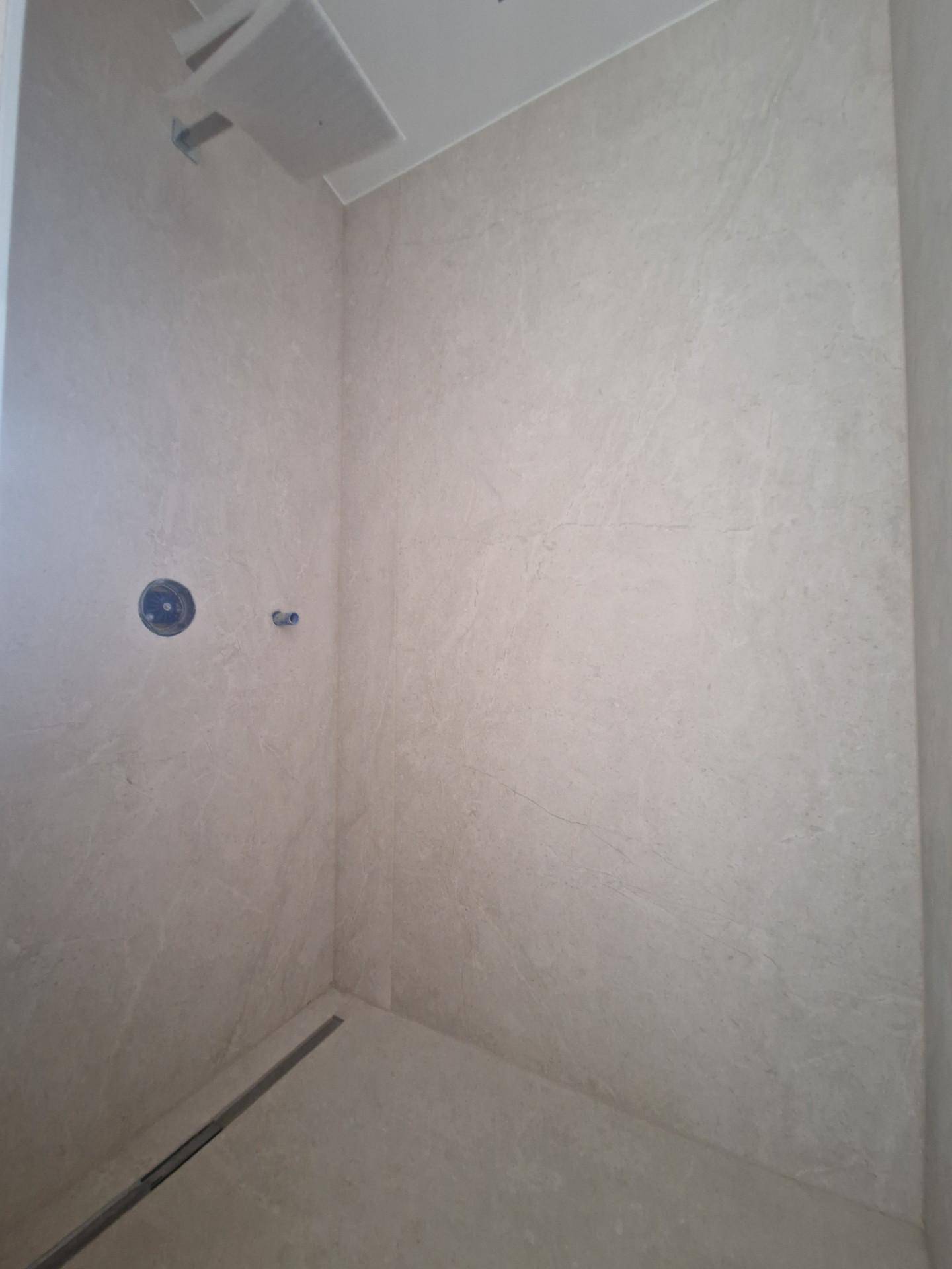 Geräumige begehbare Dusche mit modernen Fliesen und Regenbrause-Vorbereitung.