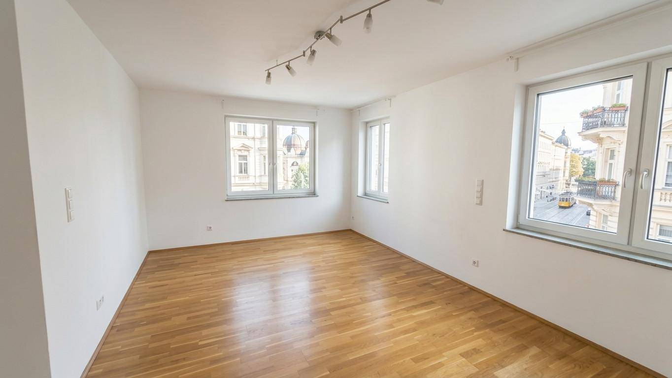 Geräumiges, helles Zimmer mit Parkettboden und mehreren Fenstern mit Stadtblick.