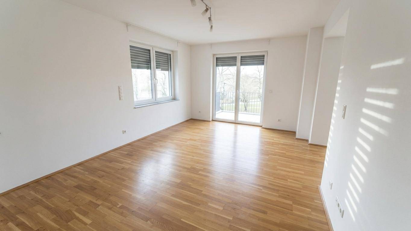 Helles Zimmer mit Parkettboden und Zugang zu einem französischen Balkon.