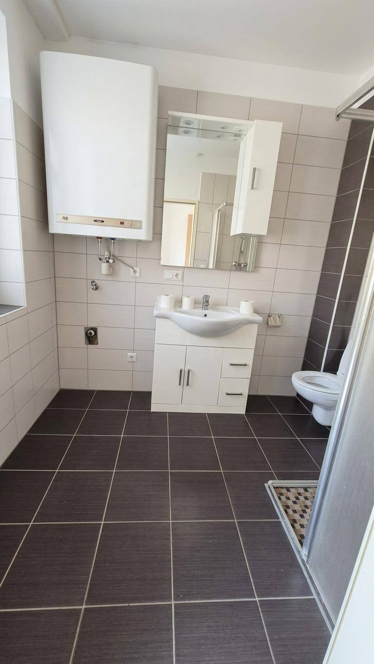 Modernes Badezimmer mit Dusche, Waschbecken und Wand-WC in neutralen Farbtönen.