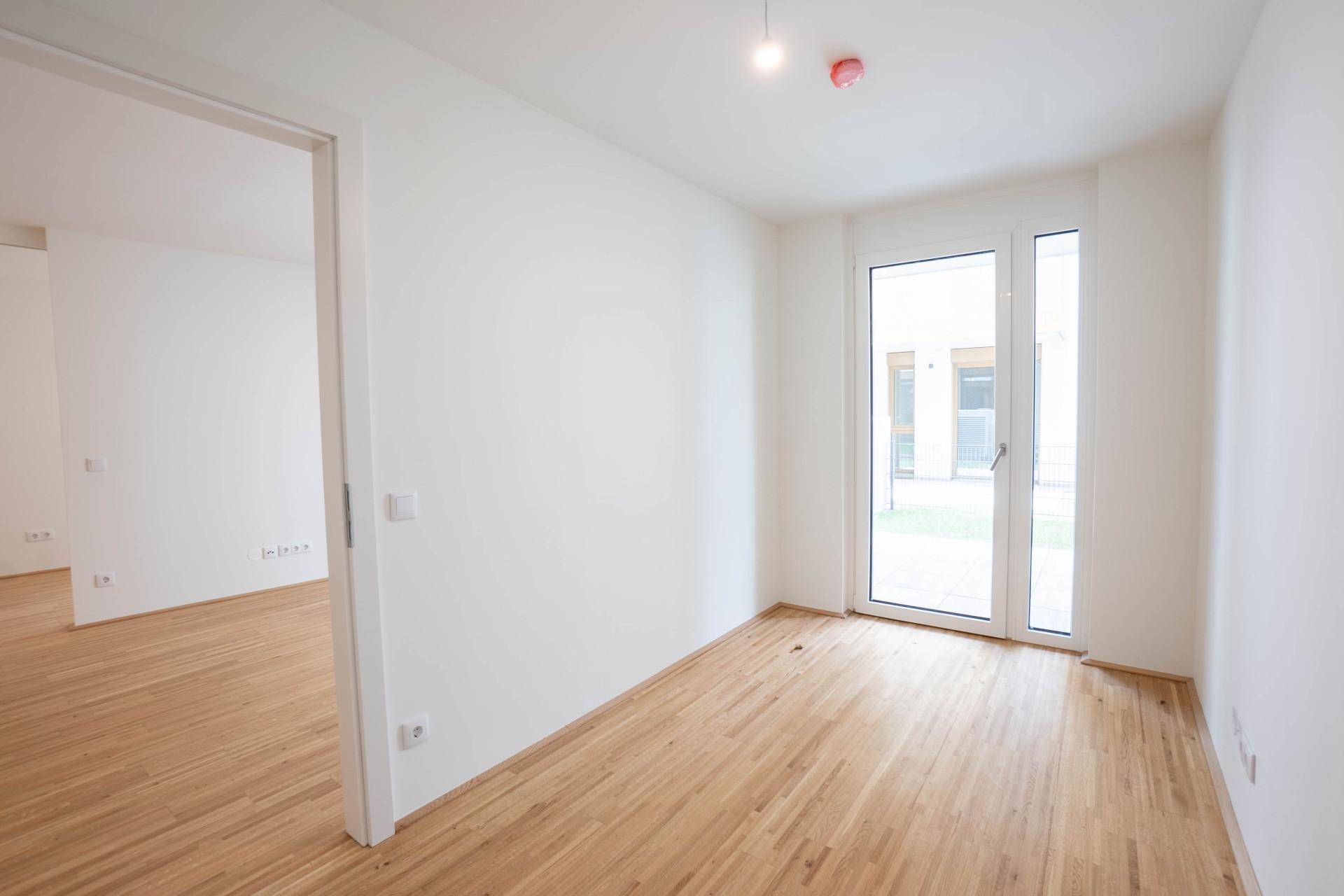 Helles Schlafzimmer mit Parkettboden und direktem Zugang zu einem Außenbereich.