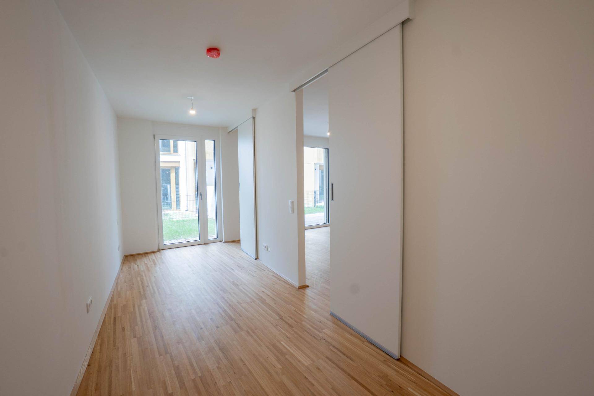 Heller Flur mit Parkettboden, Schiebetüren und Zugang zu einem Außenbereich.