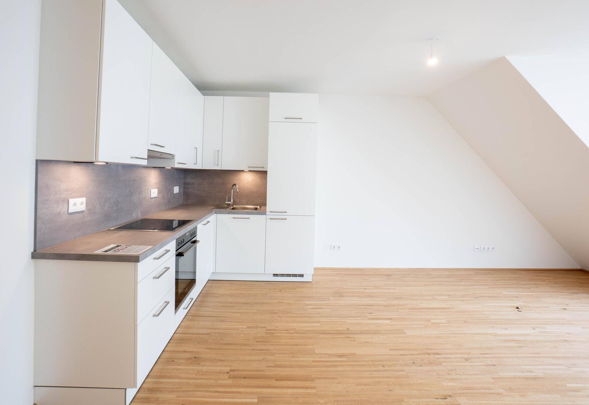 Moderne Küchenzeile mit weißen Schränken, integriertem Backofen und Induktionskochfeld.