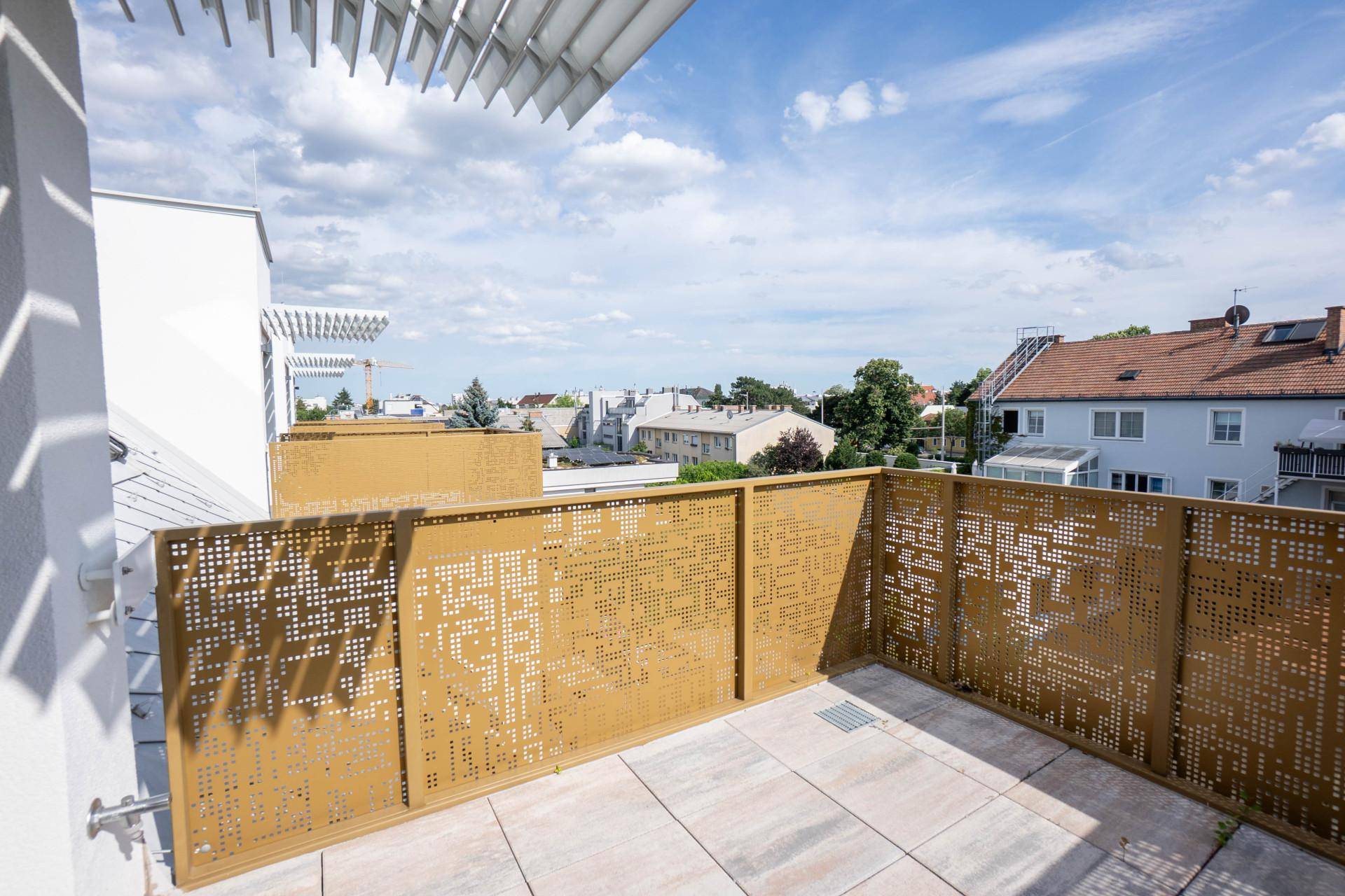 Sonniger Terrassenbereich mit dekorativen Metallgeländern, Fliesenboden und Panoramablick über die Stadt.