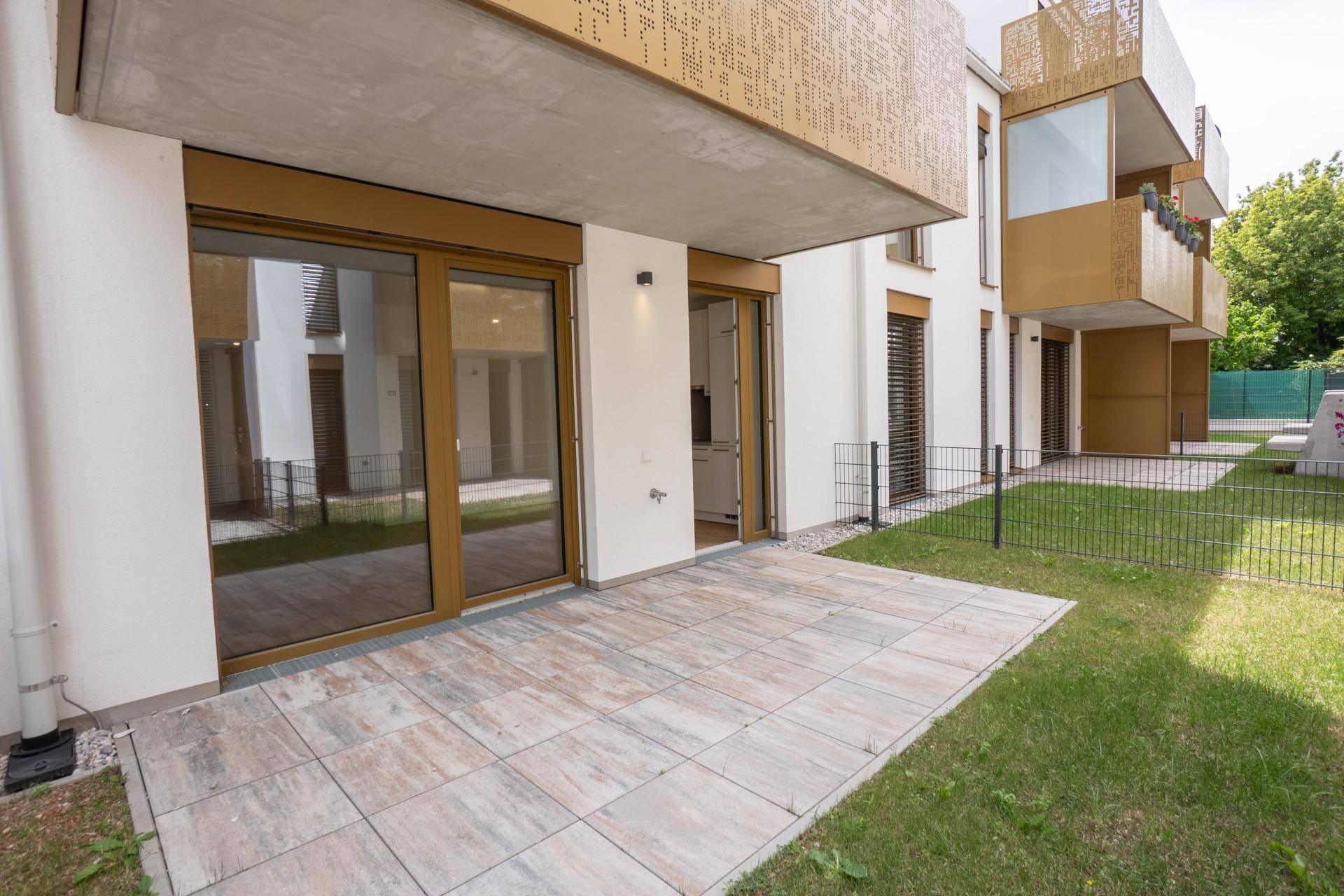 Ebenerdige Terrasse mit Steinplatten und angrenzender Rasenfläche, ideal für Entspannung.