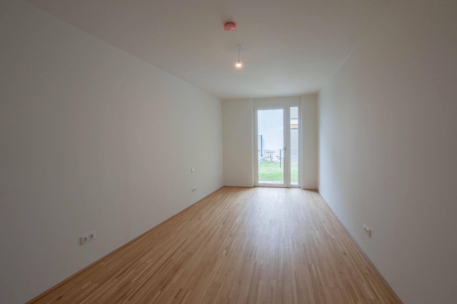 Helles Schlafzimmer mit Parkettboden und direktem Zugang zum Außenbereich.