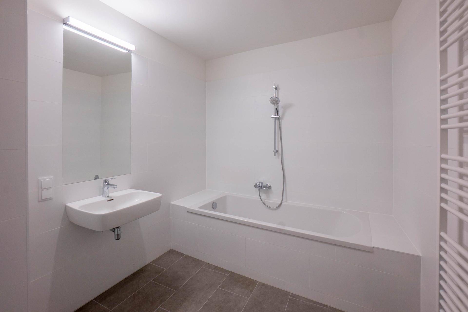 Modernes Badezimmer mit Badewanne, Waschbecken und beheiztem Handtuchhalter.