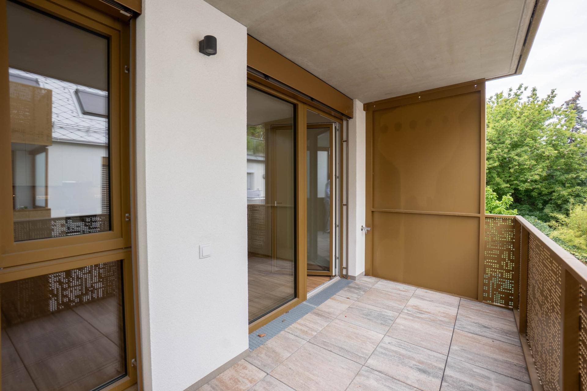 Geräumiger Balkon mit Fliesenboden und dekorativem Metallgeländer.