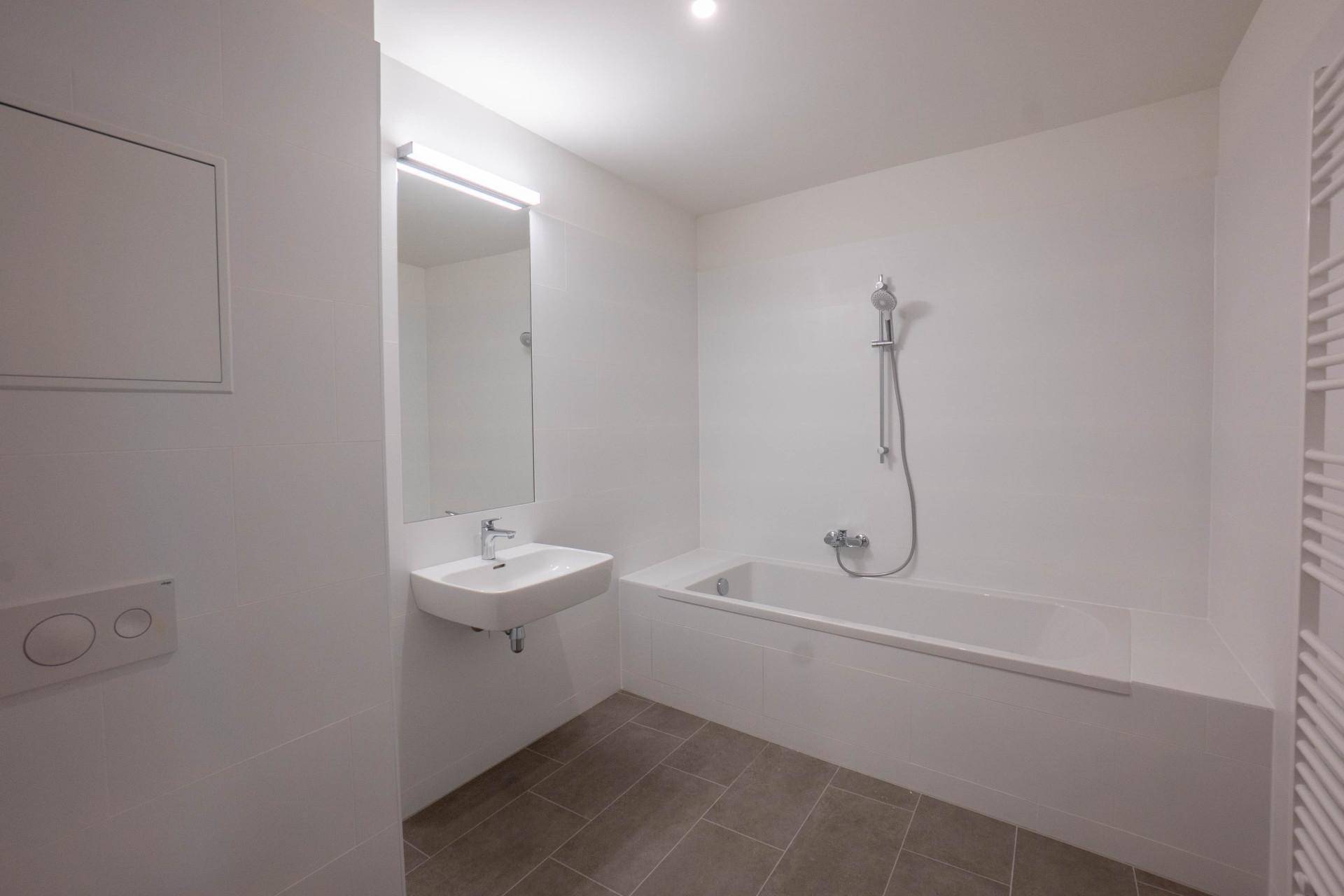 Modernes Badezimmer mit Badewanne, Wandwaschbecken und Handtuchheizkörper.