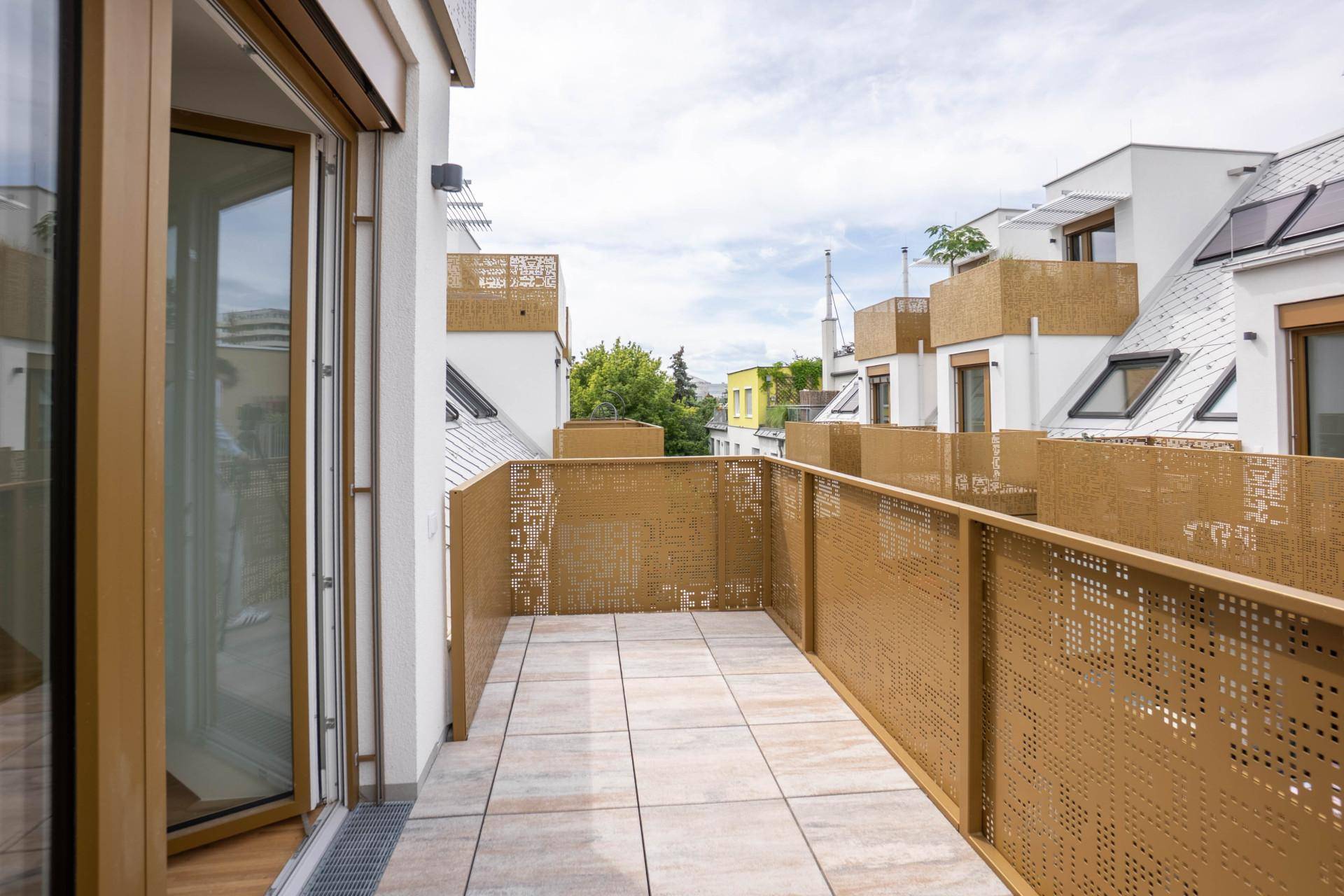 Geräumiger Balkon mit moderner goldener Brüstung und Blick auf die umliegenden Gebäude.