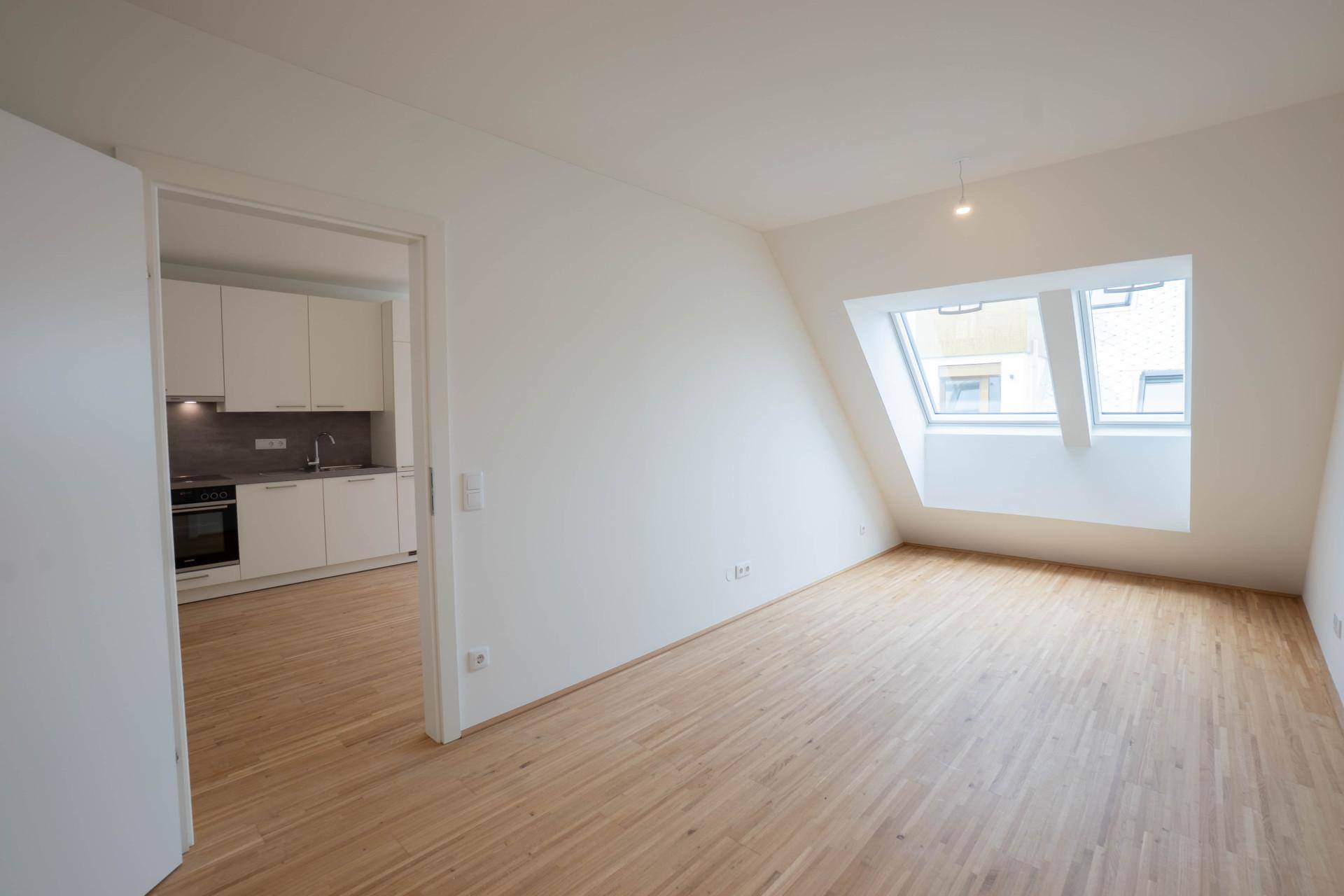 Geräumiger Wohnbereich mit Holzboden und großen Dachfenstern, die viel Tageslicht hereinlassen.