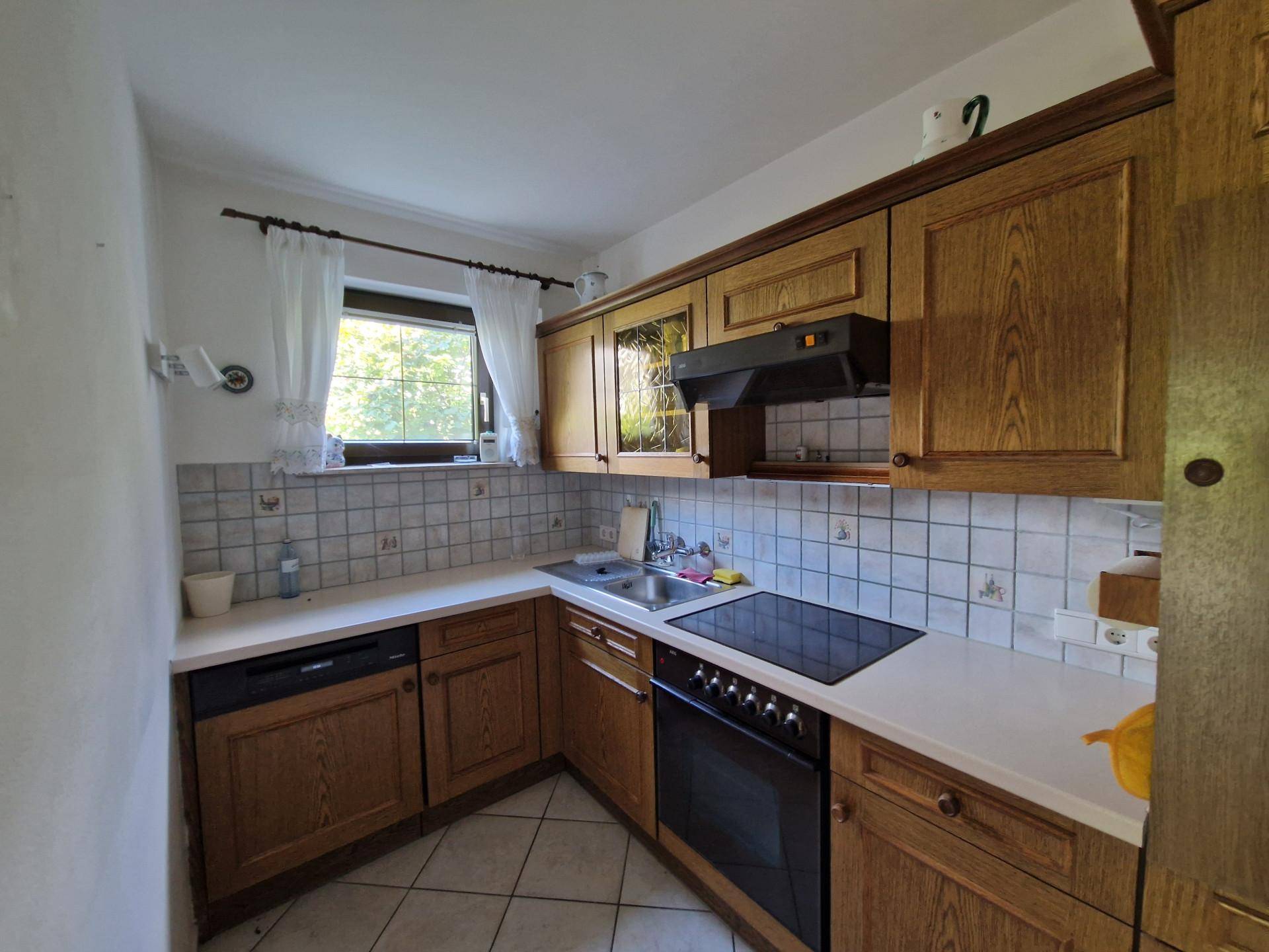 Küche im traditionellen Stil mit Holzschränken, Fliesenrückwand und Fenster.