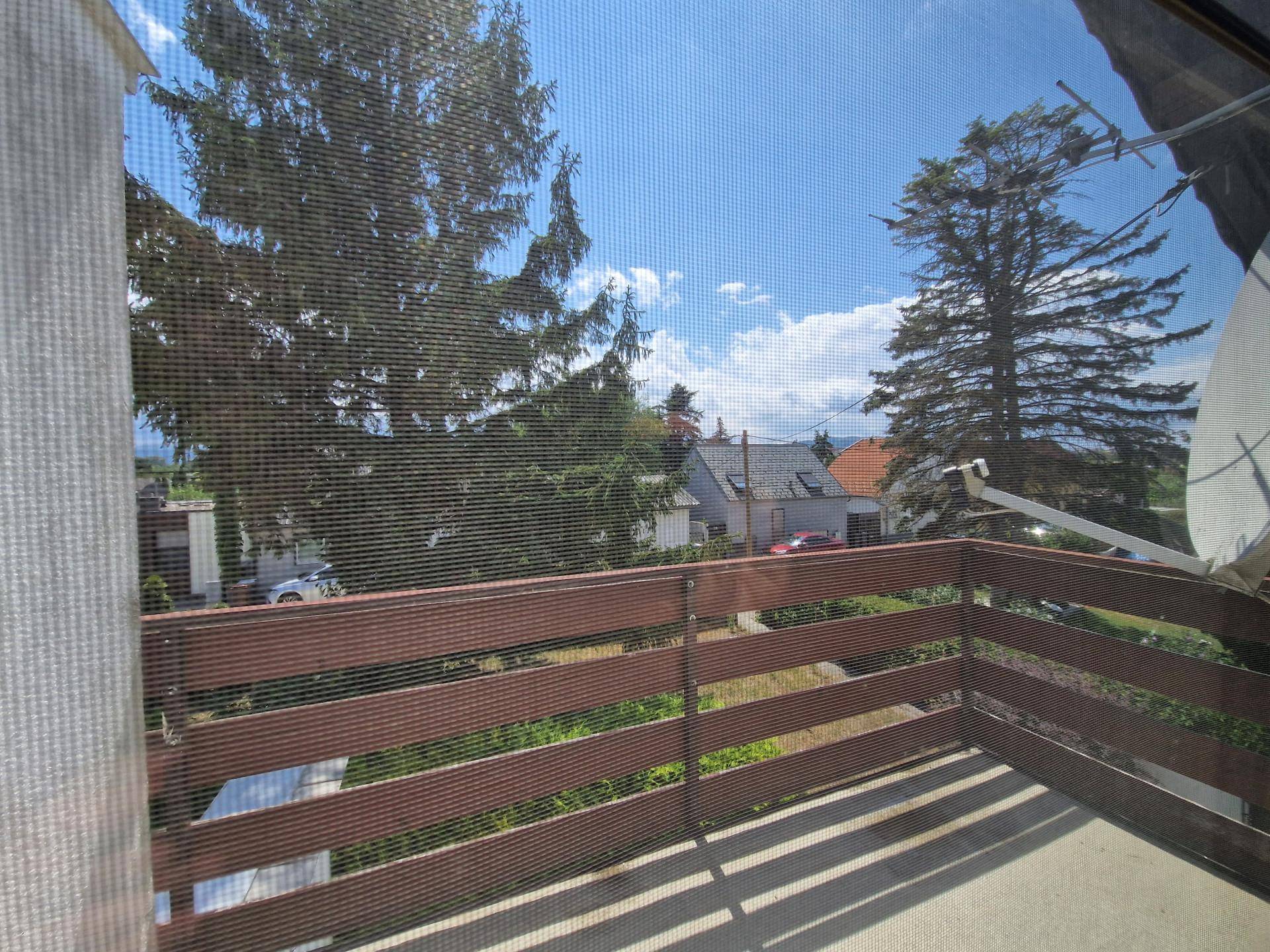 Balkon mit Holzgeländer und Blick auf die umliegende Nachbarschaft und Bäume.