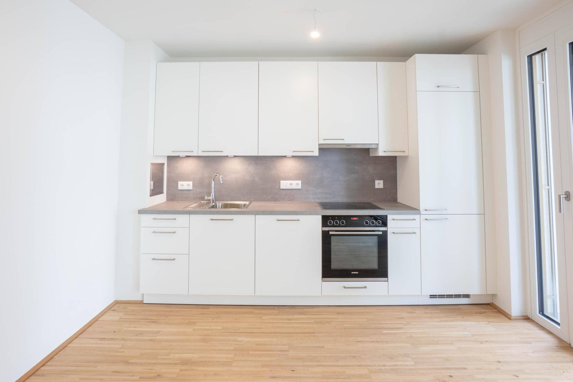 Moderne Einbauküche in Weiß mit integrierten Geräten und Holzparkettboden.